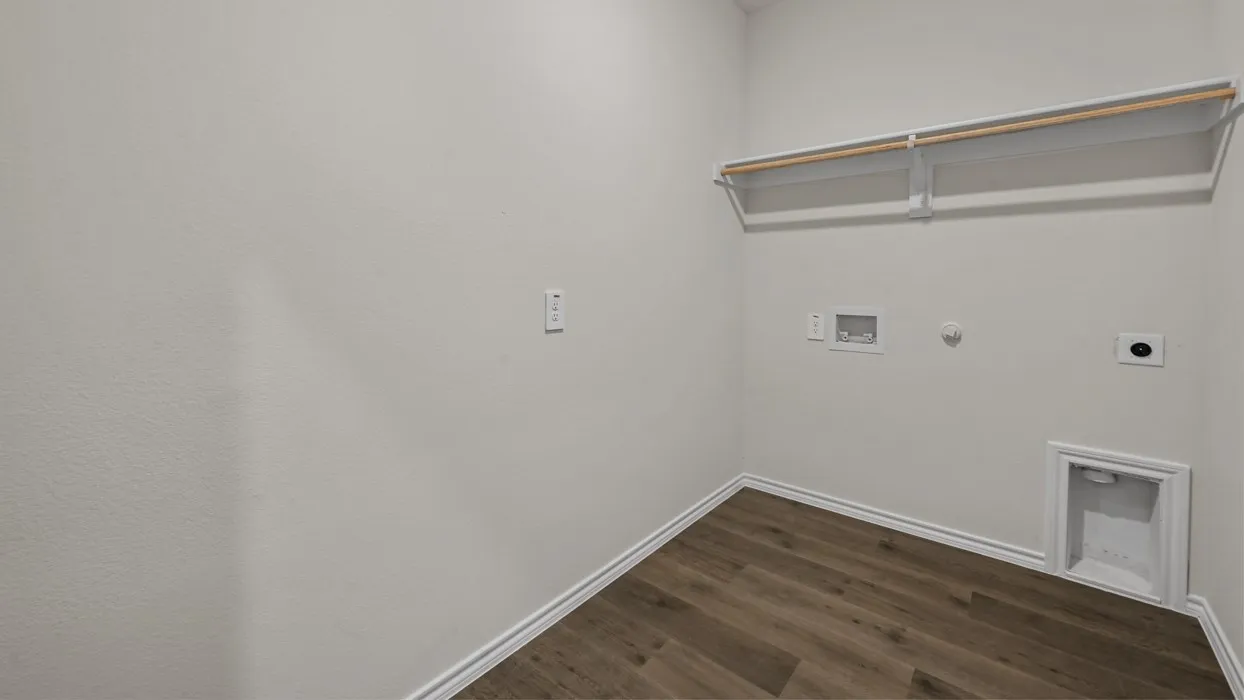 Dedicated laundry area featuring wood-finish flooring, white walls, and a built-in shelving unit with a hanging rod