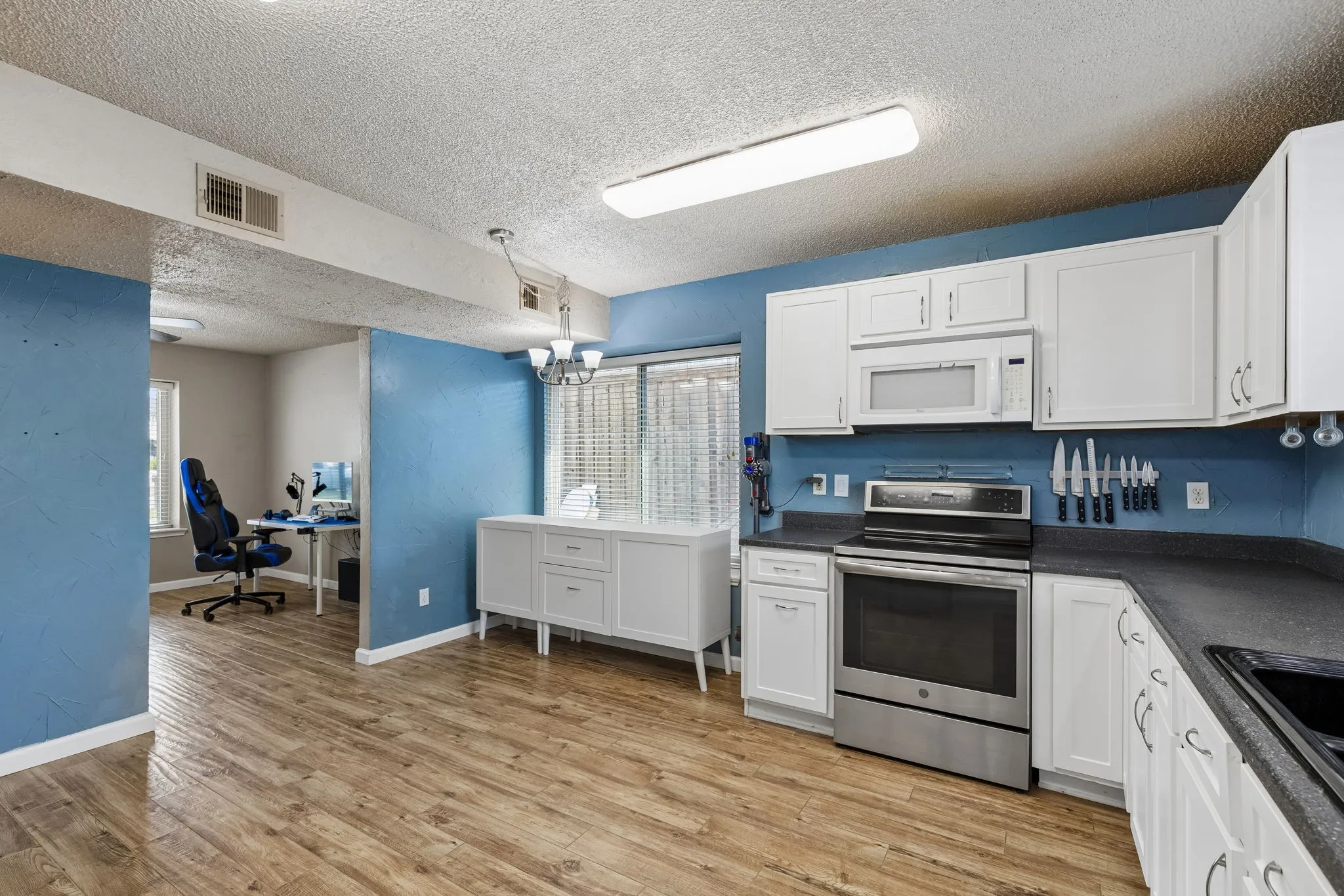 Kitchen featuring dark countertops, stainless steel electric range, an office area, a textured ceiling, and white cabinets