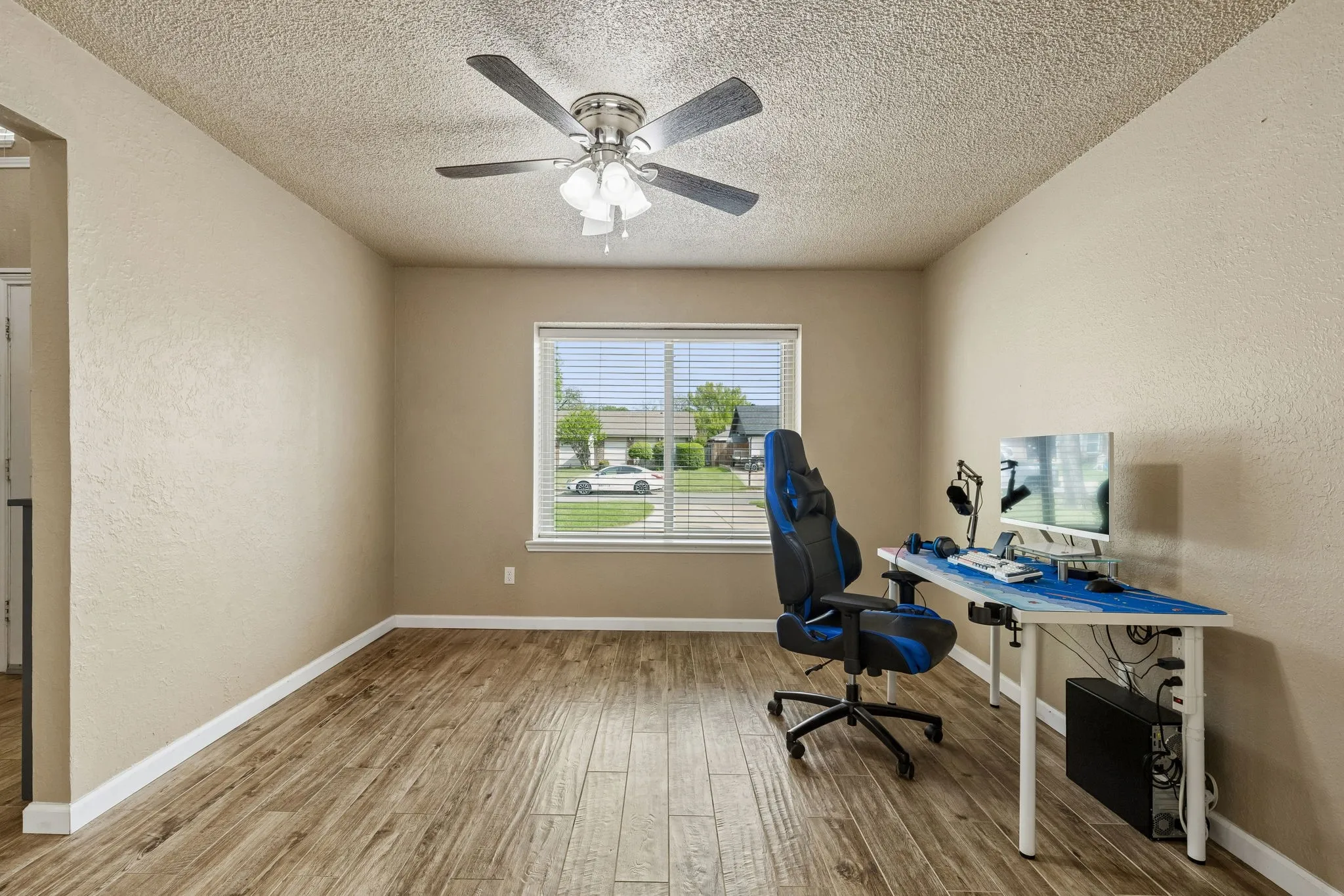 Unfurnished office with a textured wall, a textured ceiling, ceiling fan, and light wood-type flooring