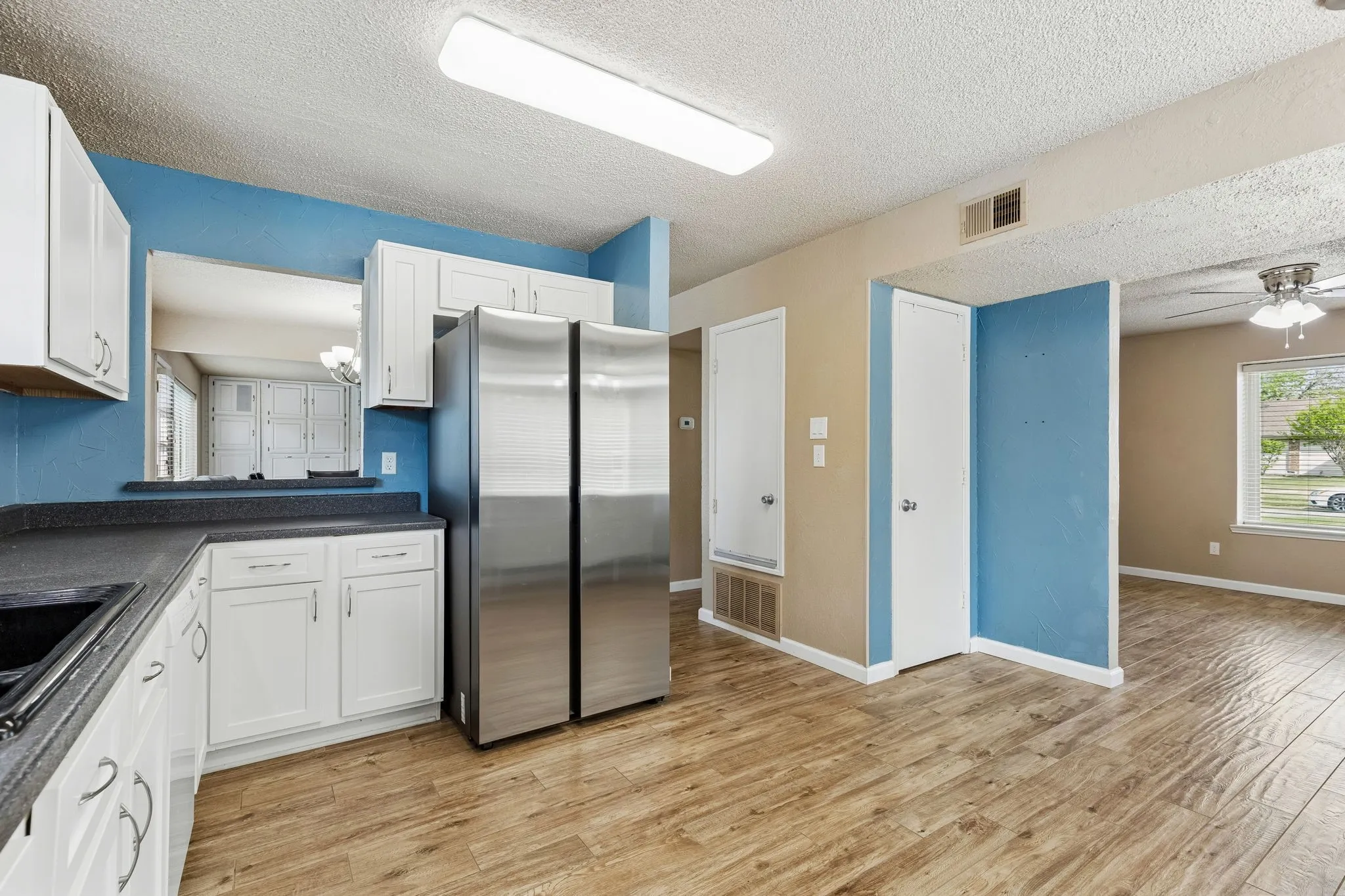 Kitchen featuring dark countertops, plenty of natural light, freestanding refrigerator, a ceiling fan, and a textured ceiling