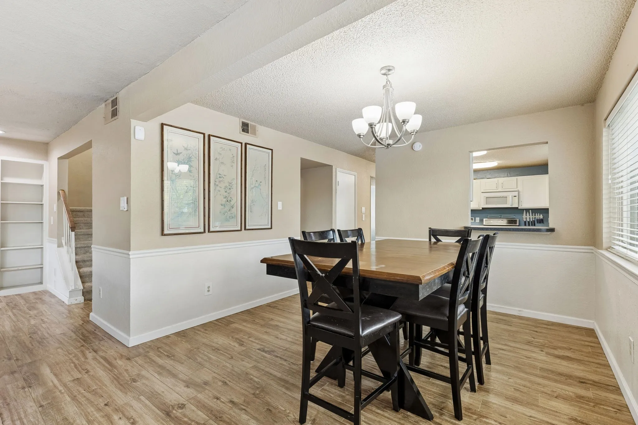 Dining space featuring light wood-type flooring, a textured ceiling, and suspended lighting