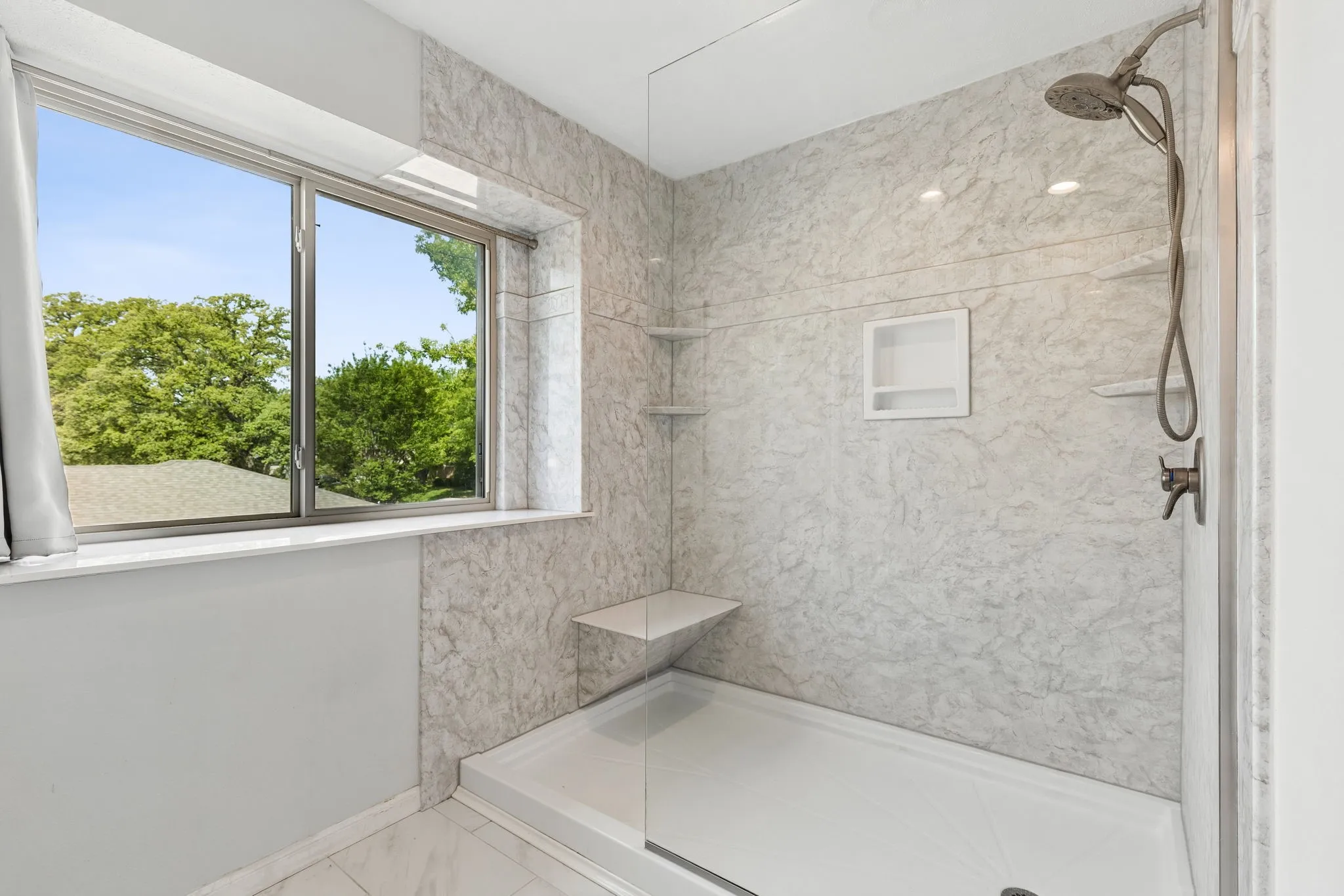 Full bath with a marble finish shower and light marble finish flooring