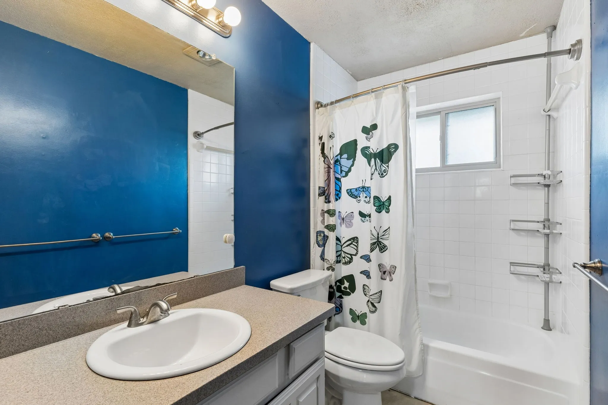 Bathroom with vanity, shower / bath combo, and a textured ceiling