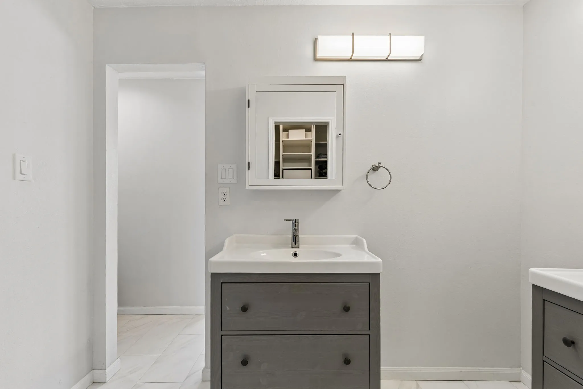 Bathroom with vanity and light marble finish flooring