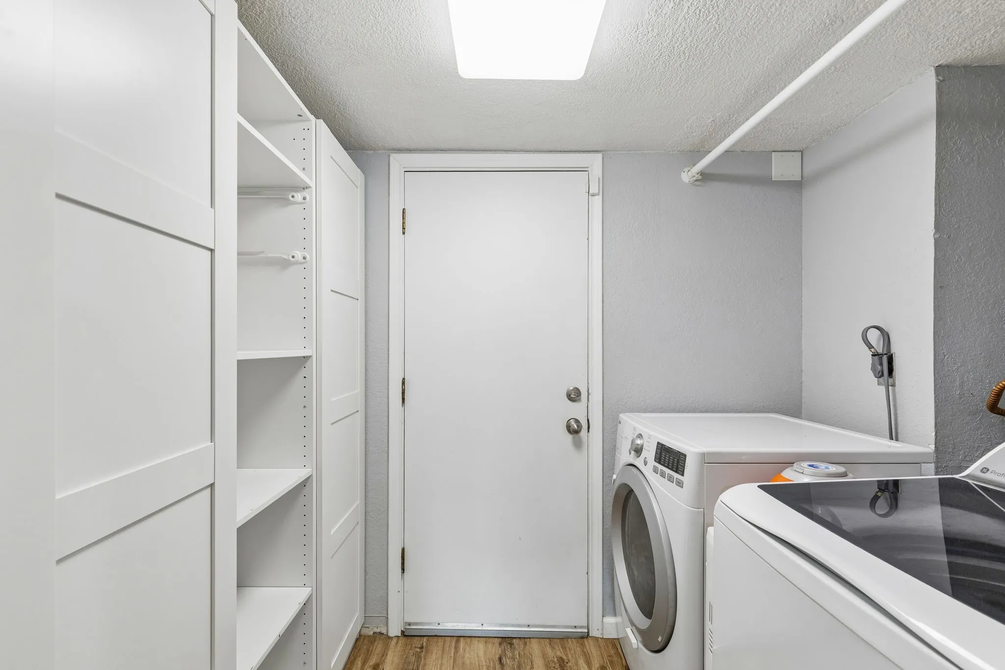 Laundry room with a textured ceiling, light wood-style floors, and washer and clothes dryer