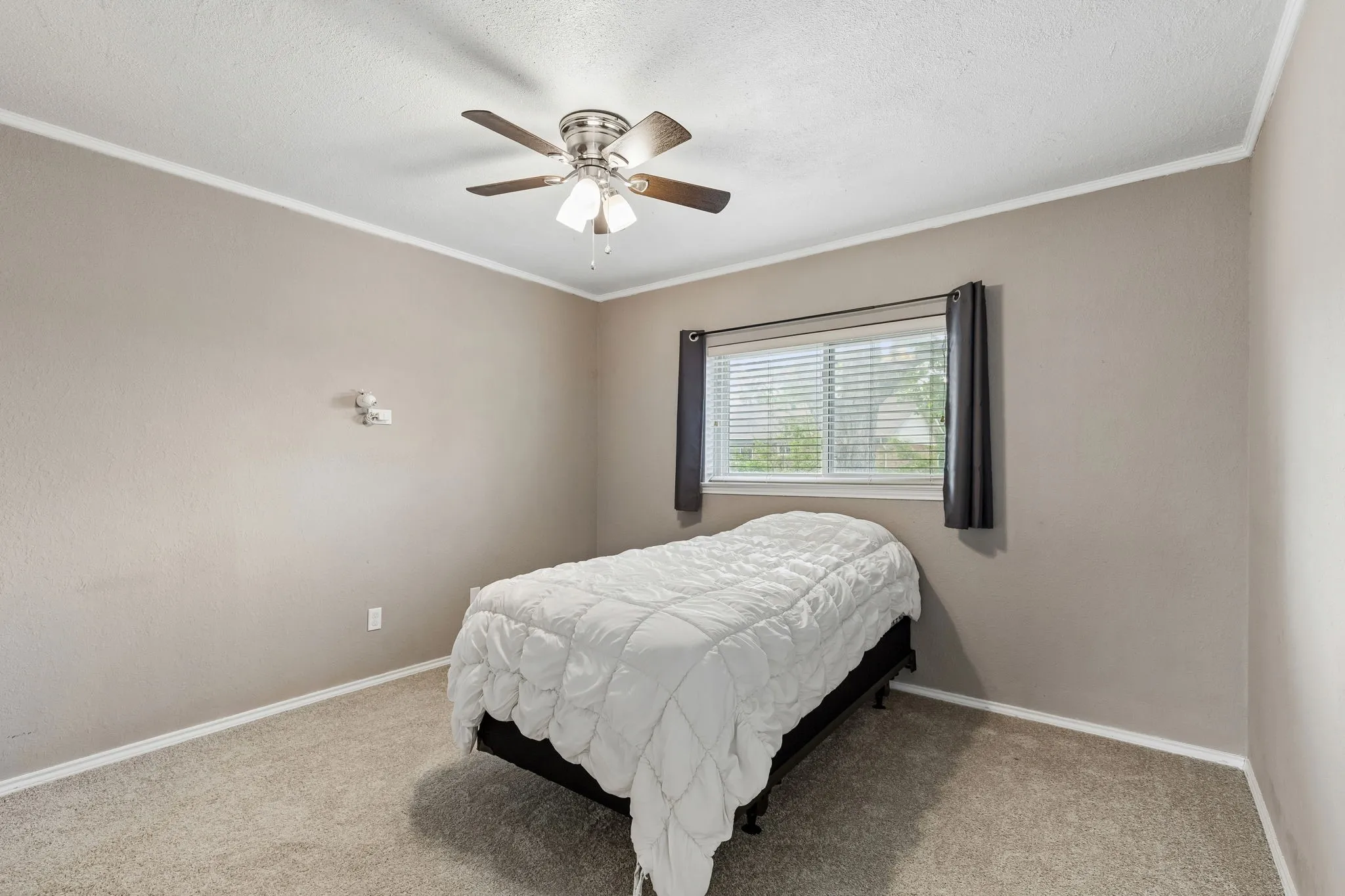 Bedroom with ceiling fan, crown molding, carpet, and a textured ceiling