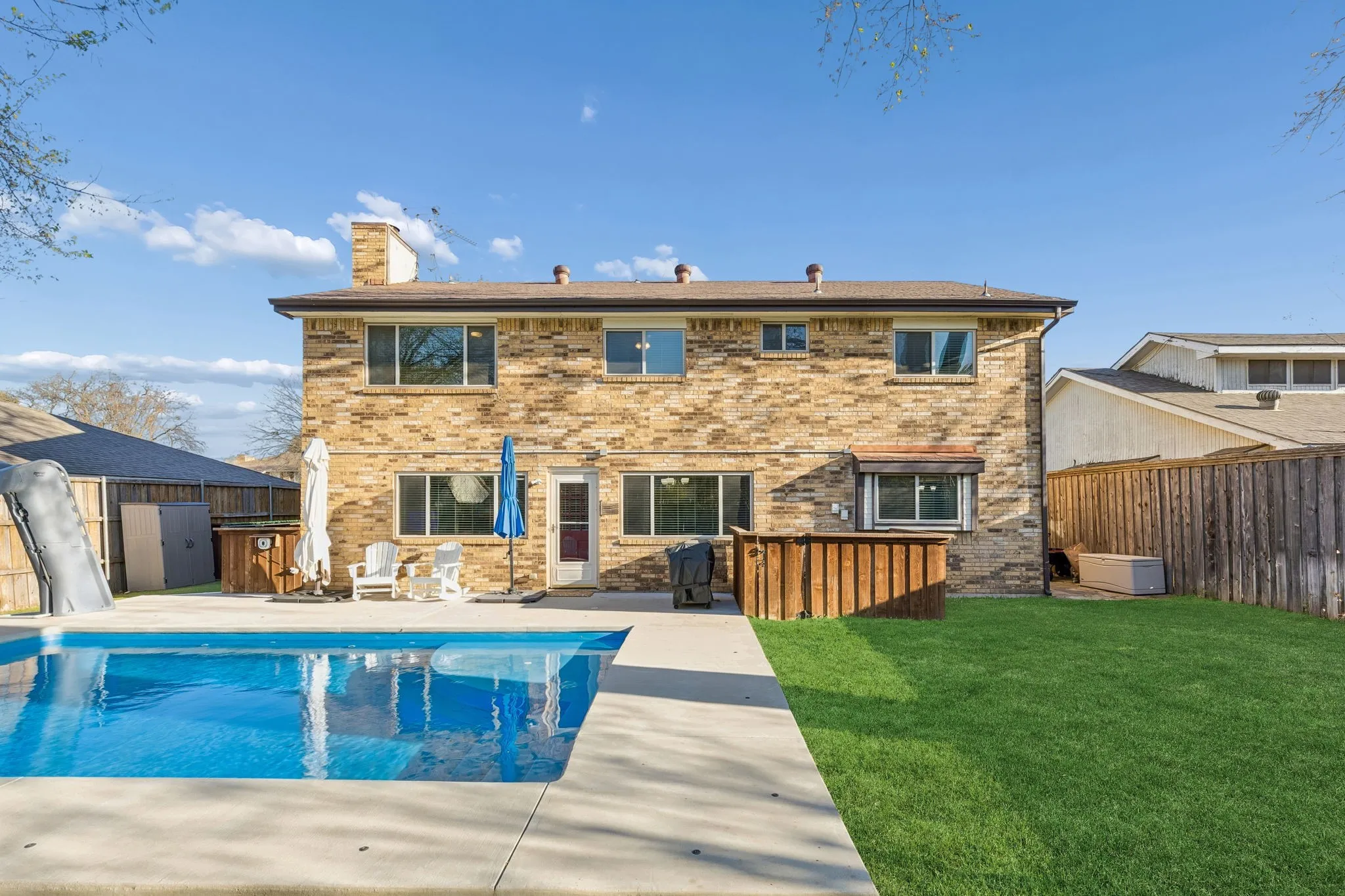 Back of property featuring brick siding, a fenced backyard, a chimney, and a patio