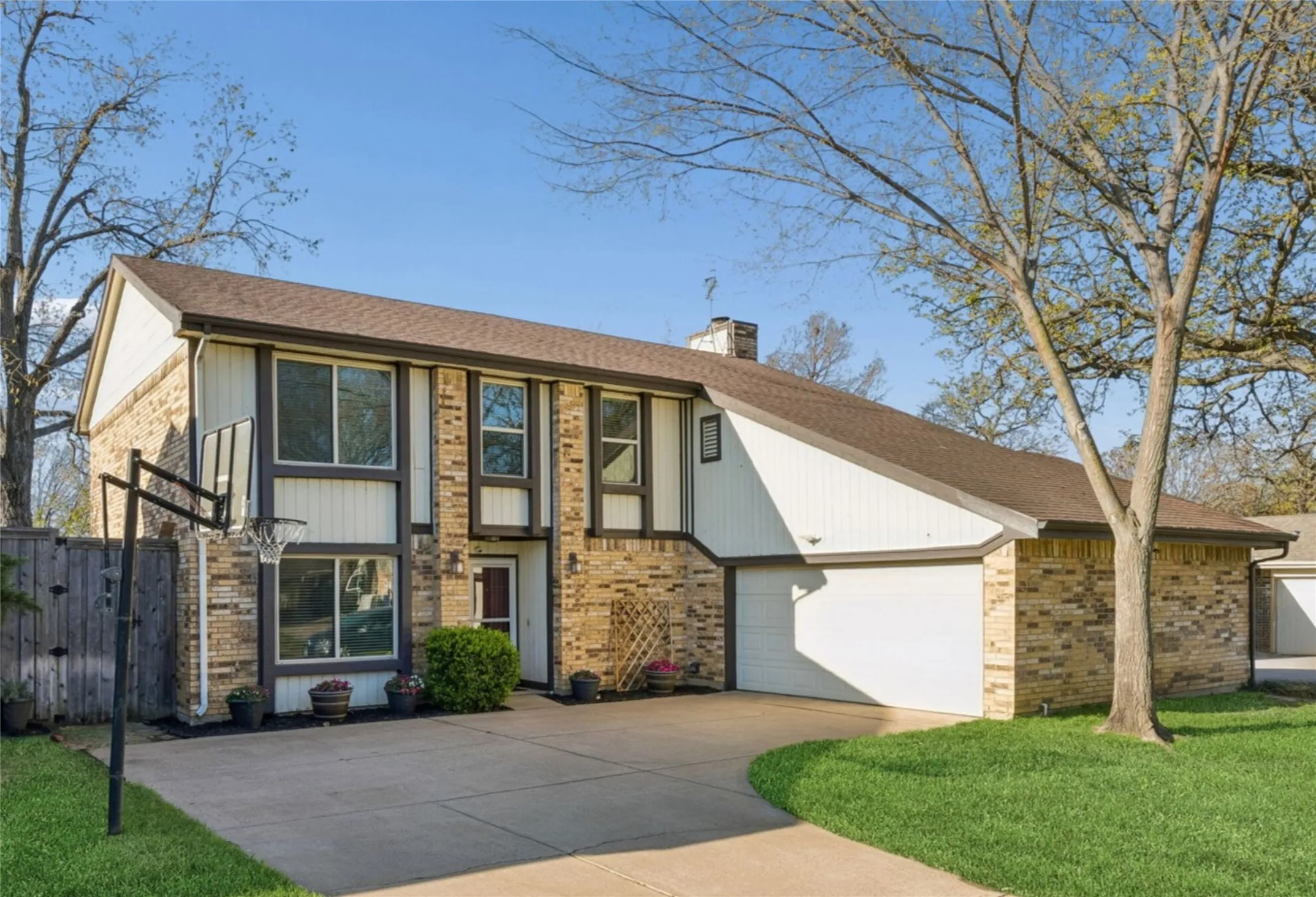 View of front facade with concrete driveway, a chimney, a garage, and brick siding
