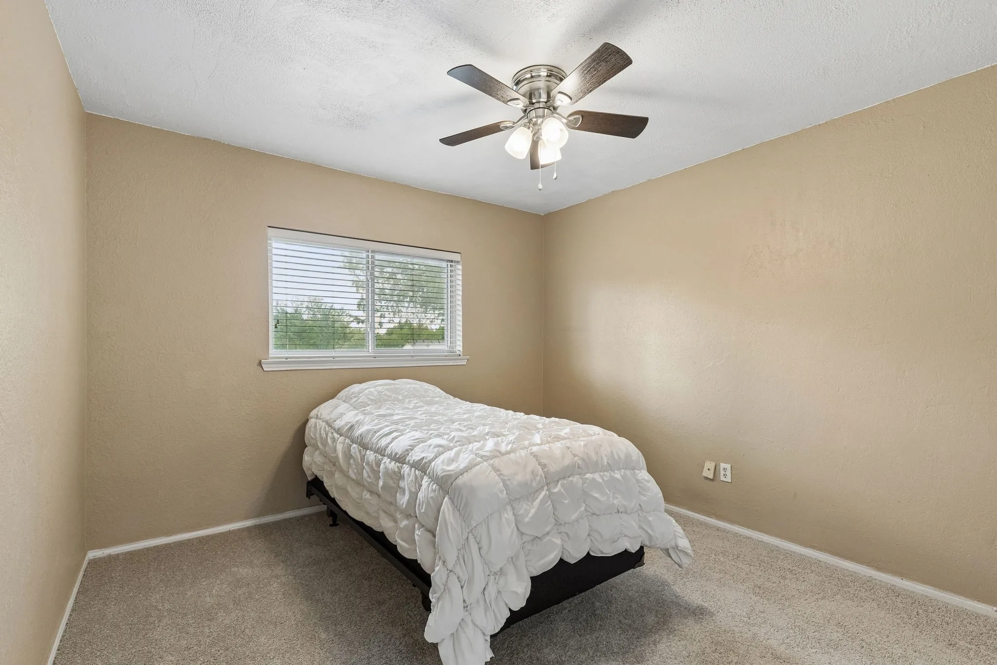Bedroom with ceiling fan, carpet, and a textured wall