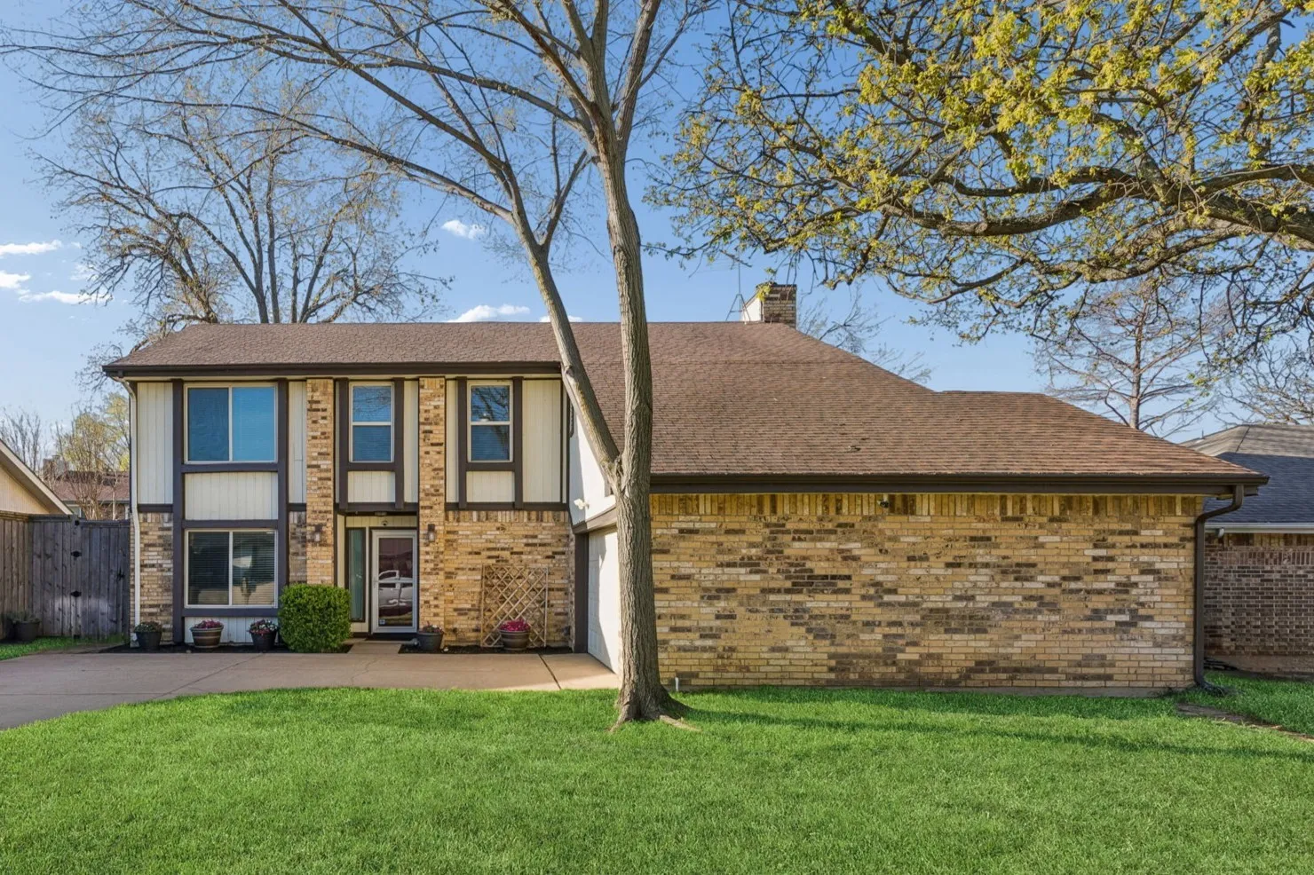 View of front of property featuring a chimney, brick siding, and driveway