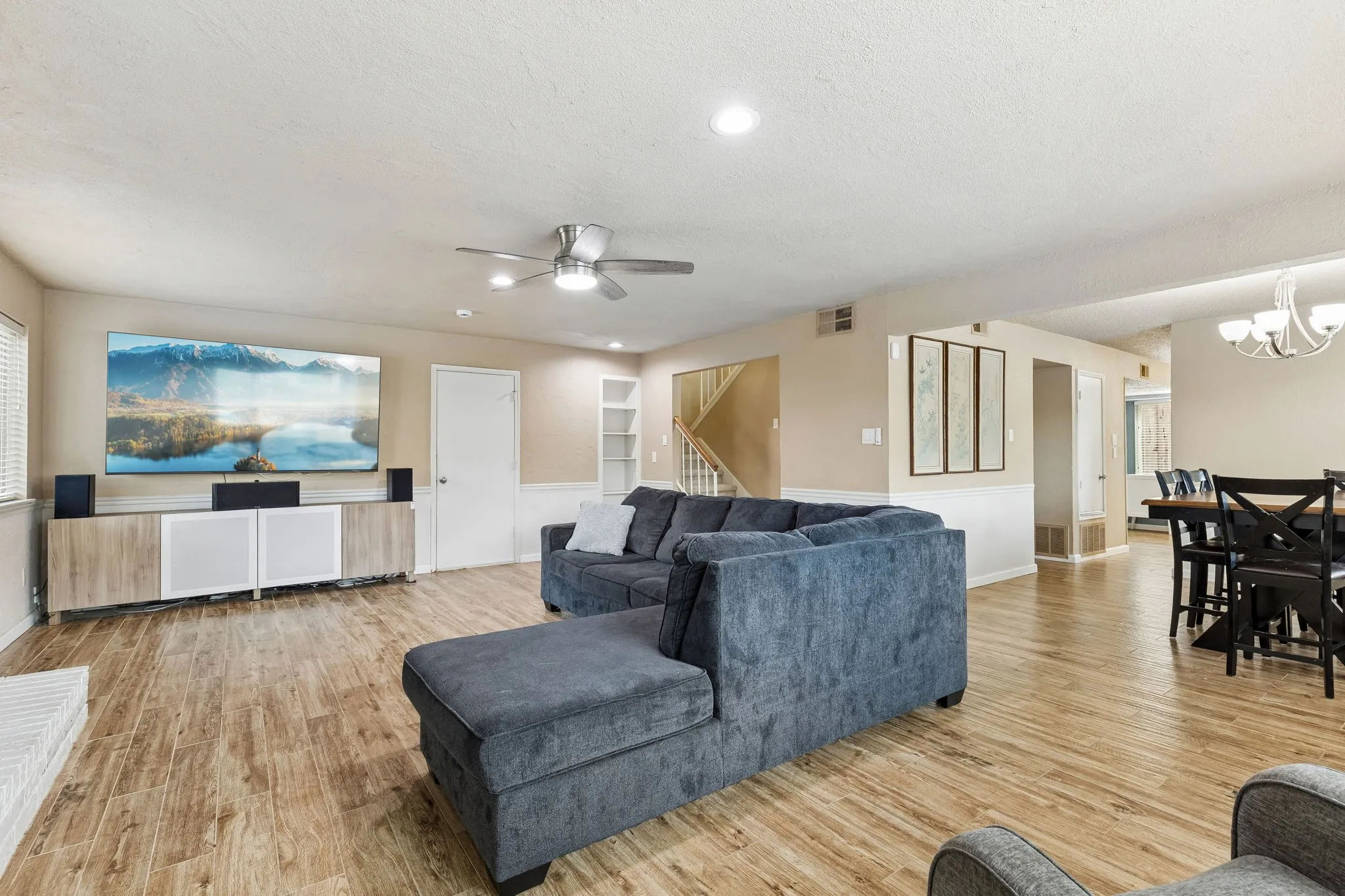 Living room featuring light wood-type flooring, a ceiling fan, a textured ceiling, and a chandelier