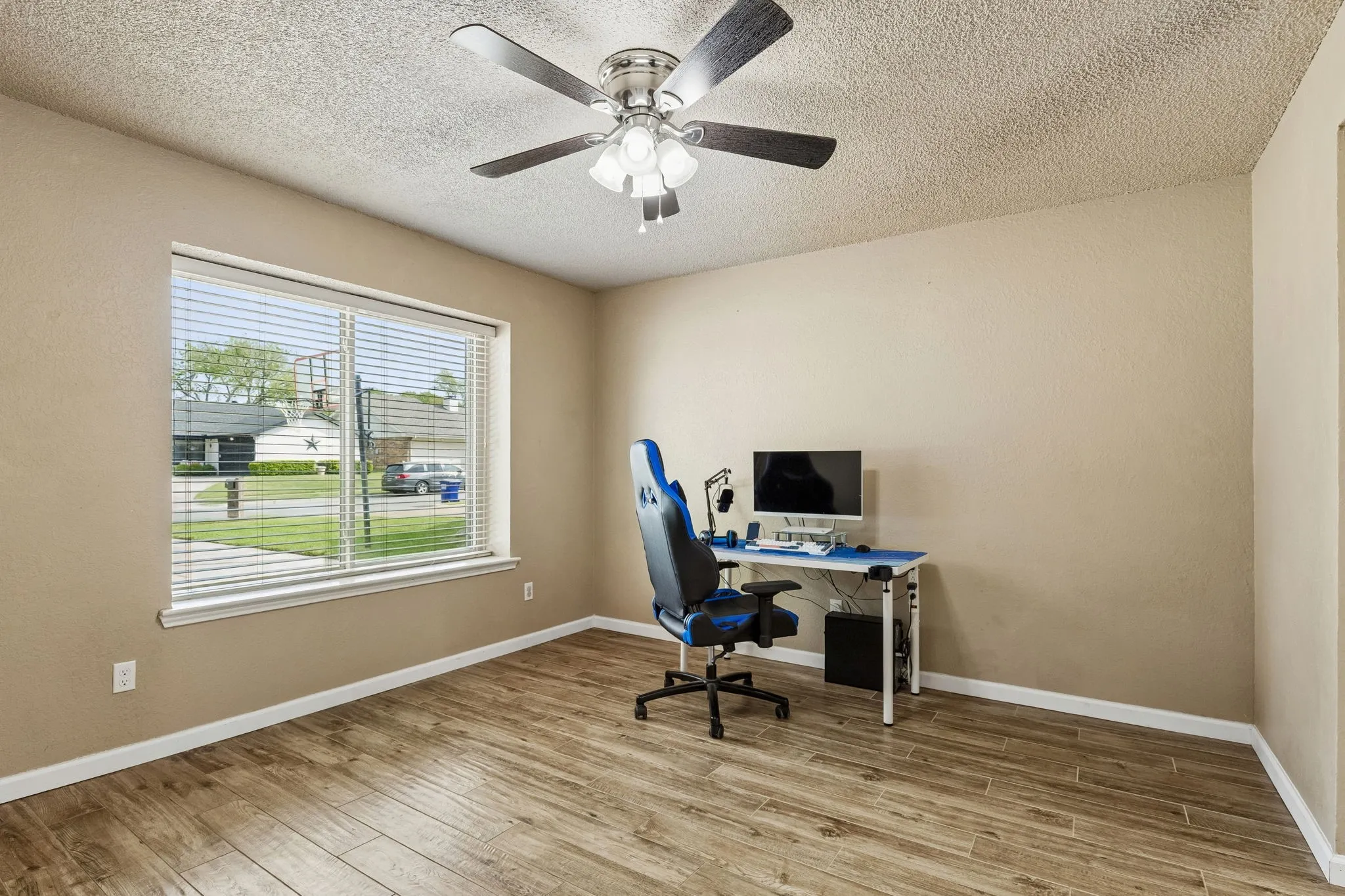 Home office with light wood-type flooring, a textured ceiling, and ceiling fan