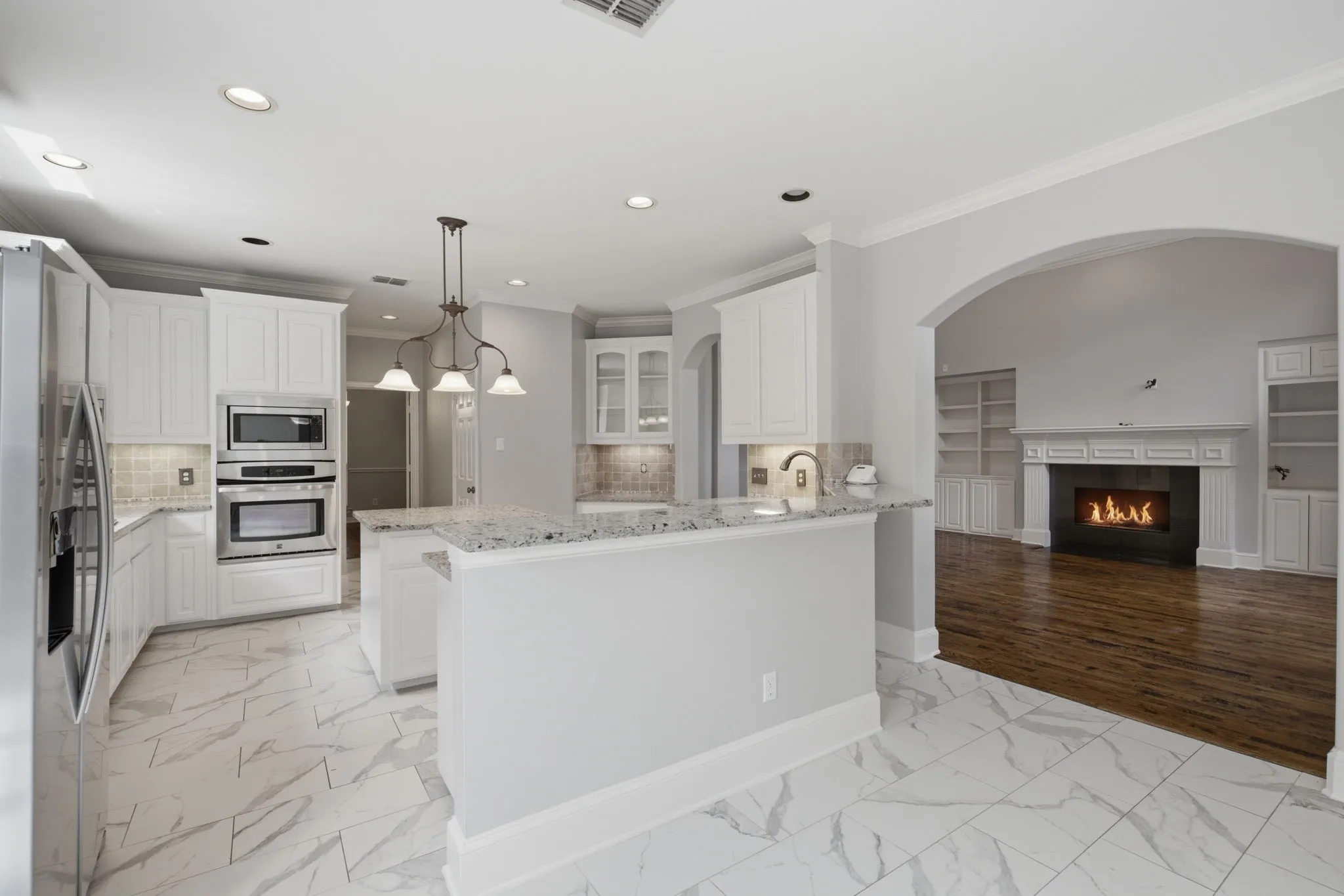 This beautifully sunlit perspective captures the seamless flow from the breakfast nook, offering a clear and inviting view directly into the modern kitchen and the spacious, cozy family room, perfectly highlighting the open-concept layout of the home.