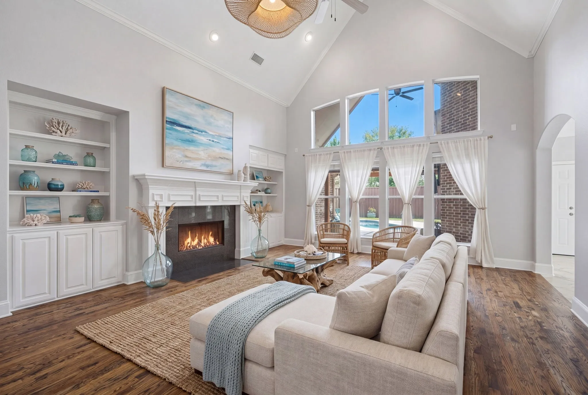 This expansive and inviting family room serves as the heart of the home, featuring a stunning vaulted ceiling that enhances the sense of openness and airiness. A grand, centered fireplace acts as a sophisticated focal point, beautifully flanked by custom built-in shelving perfect for displaying décor or personal collections. The rear wall is thoughtfully designed with a double row of oversized windows that flood the space with natural light while providing picturesque views of the private backyard oasis, including the pristine swimming pool, charming pergola, and spacious patio area. All of this is tied together by elegant, high-quality hardwood flooring that flows seamlessly throughout the entire room, offering both durability and a warm, timeless aesthetic.
virtually staged