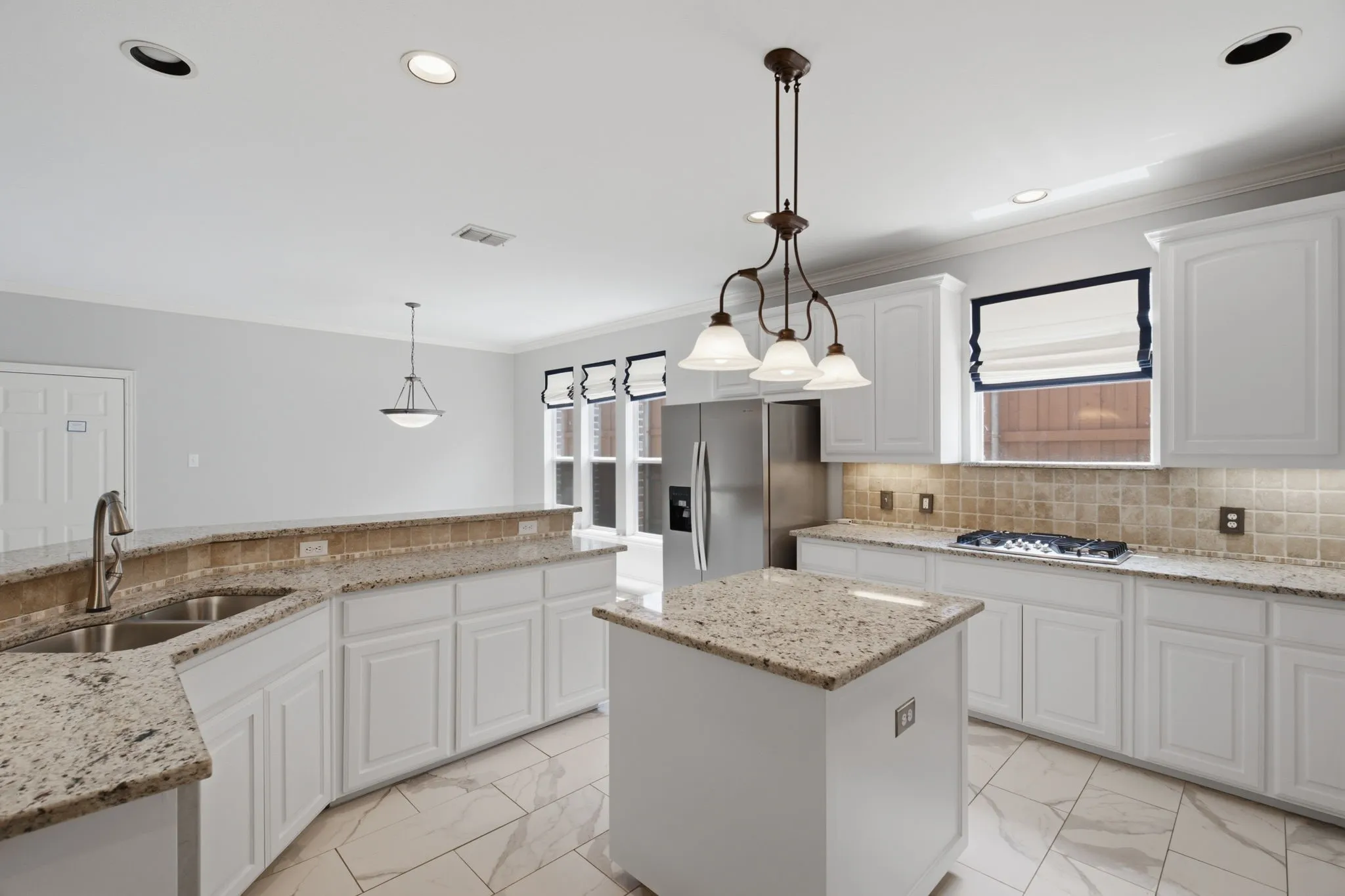 Bright and airy kitchen featuring a adjacent breakfast nook, equipped with high-end stainless steel appliances including a spacious refrigerator and a convenient window positioned perfectly above the gas cooktop for added natural light.