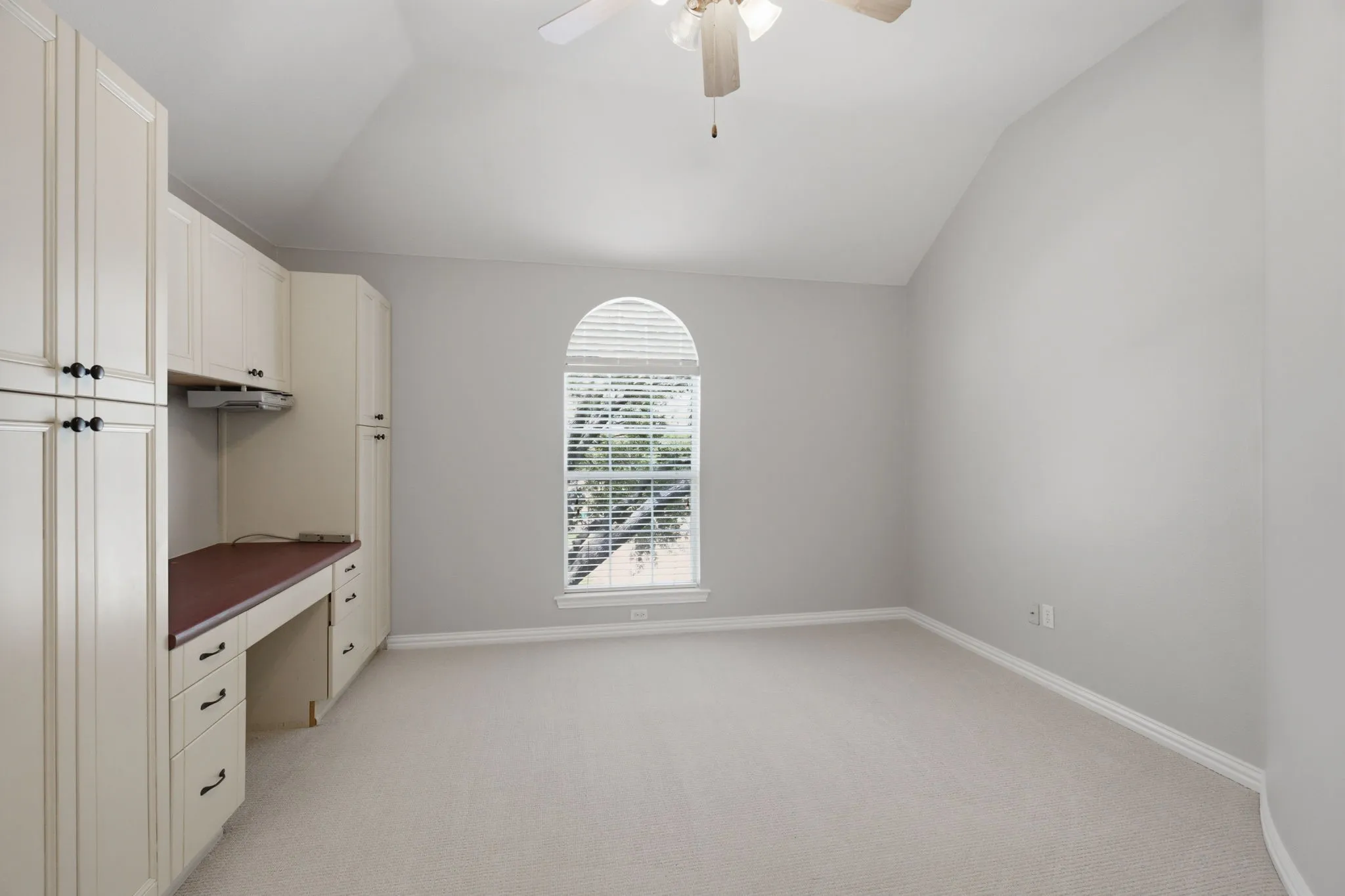 This upstairs versatile secondary bedroom features spacious vaulted ceilings that add an airy, open feel to the room. It is equipped with a ceiling fan for optimal comfort, a convenient built-in desk perfectly suited for a home office or study area, and ample integrated storage solutions to keep everything organized. Additionally, the room offers a lovely, serene view overlooking the front yard tree, bringing in plenty of natural light.