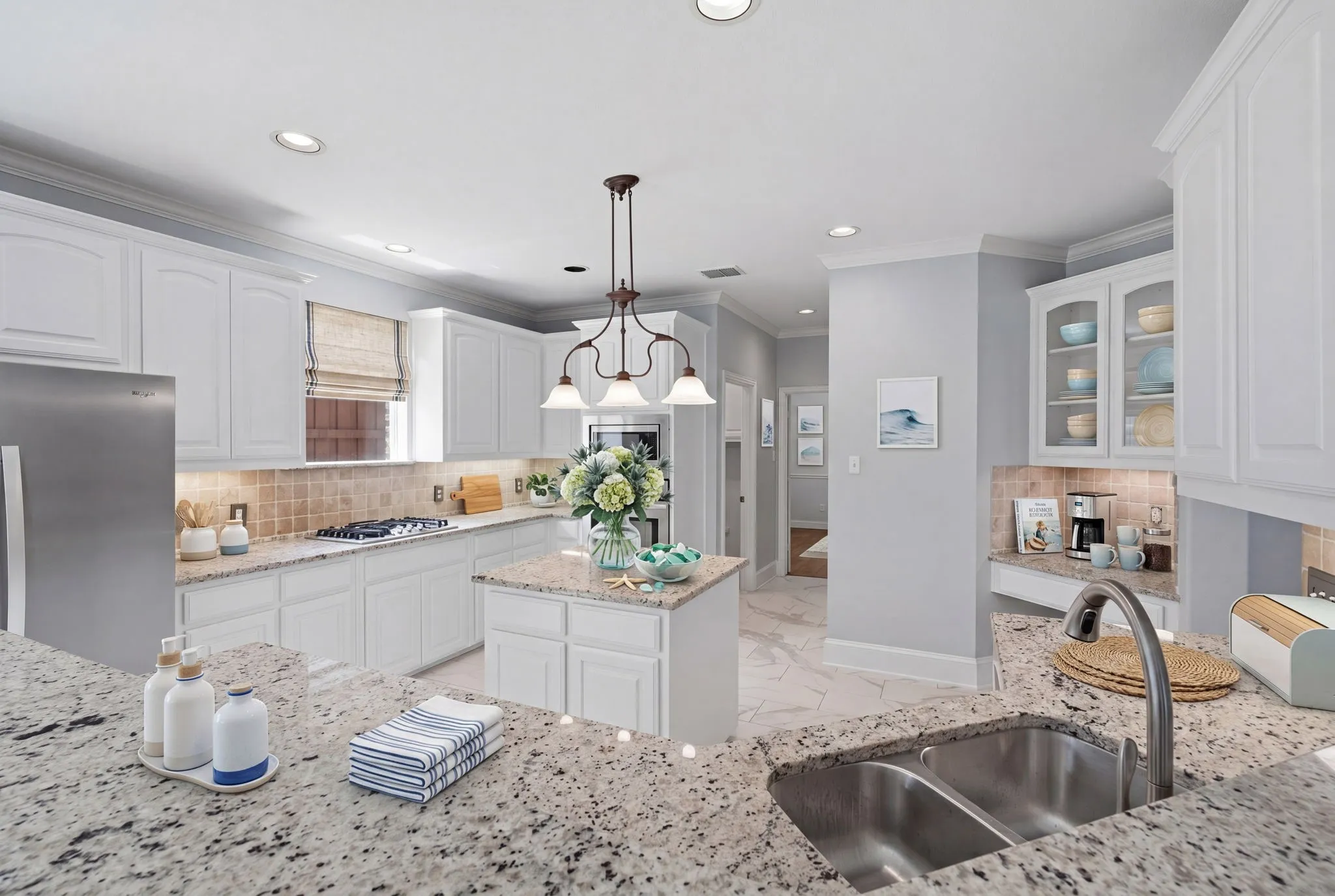 Island kitchen featuring white cabinetry, a gas cooktop, and granite countertops. The integrated desk area provides a versatile space perfect for a coffee bar.