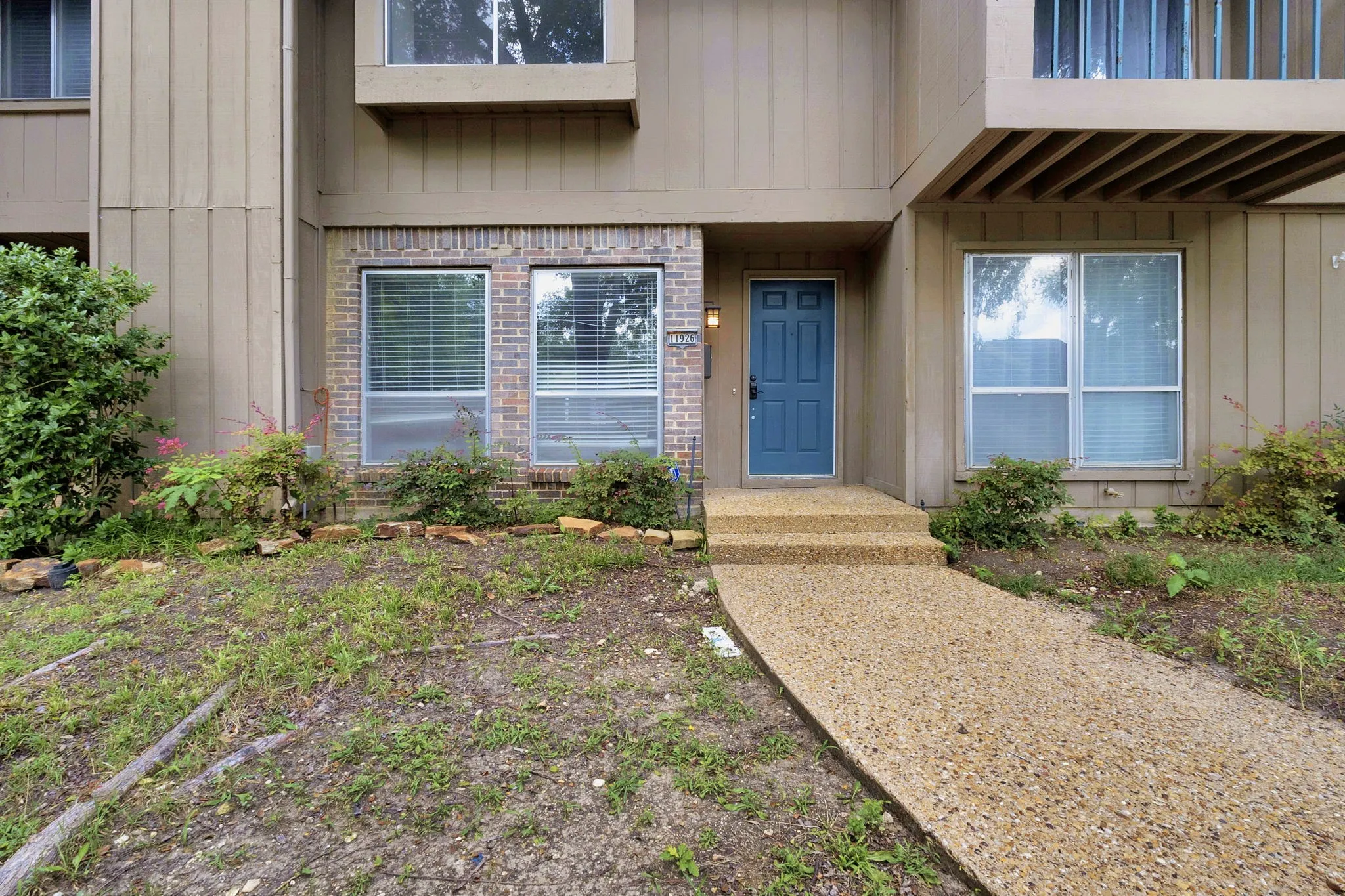 Exterior entry featuring a blue paneled door, brick facade accents, and upper-level windows