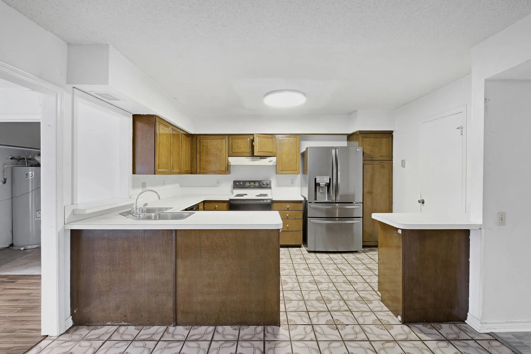 Kitchen featuring wood cabinetry, white countertops, a stainless steel refrigerator, and tiled flooring