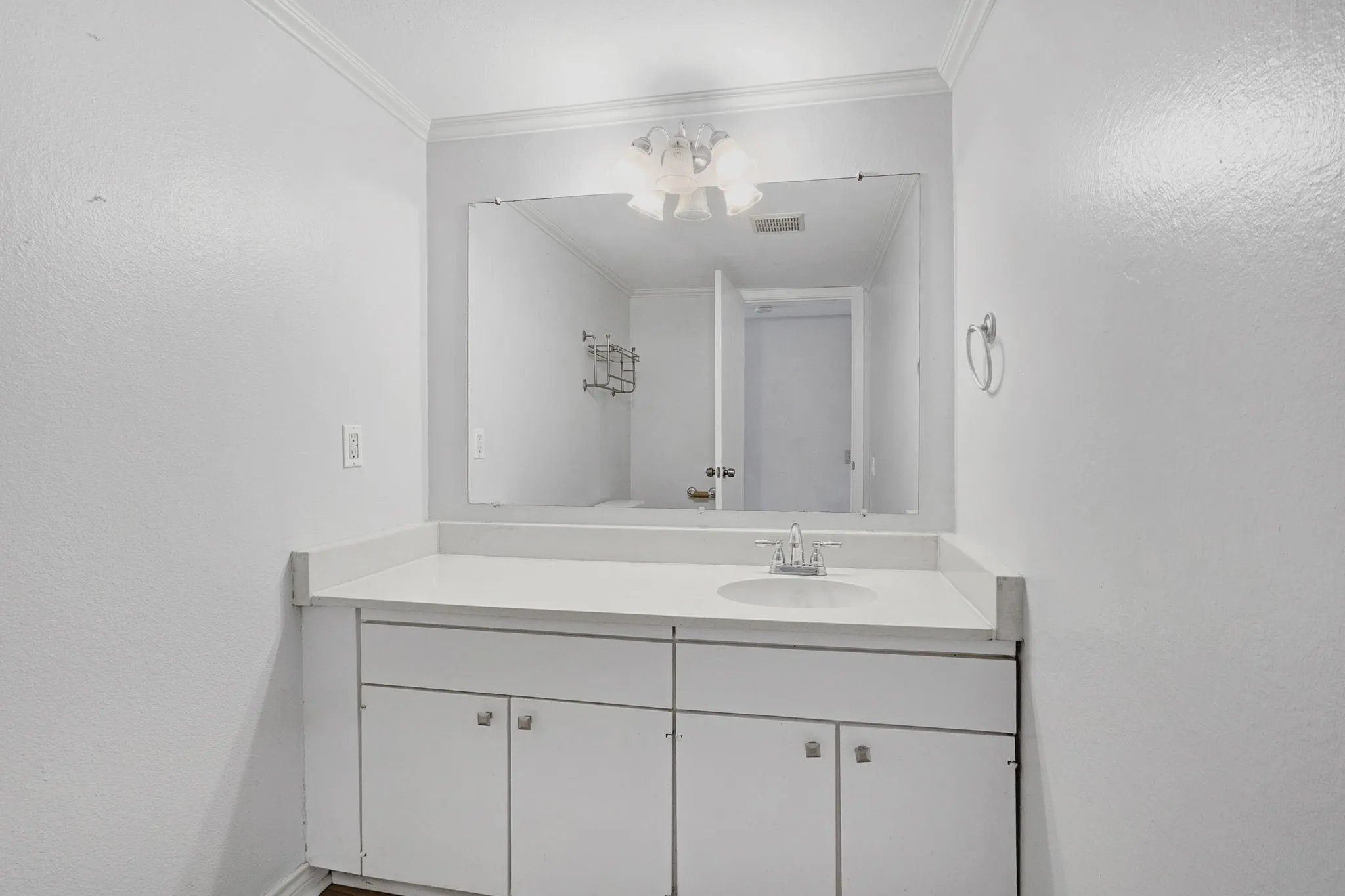 Bathroom vanity featuring an integrated sink, polished chrome faucet, and expansive wall-mounted mirror