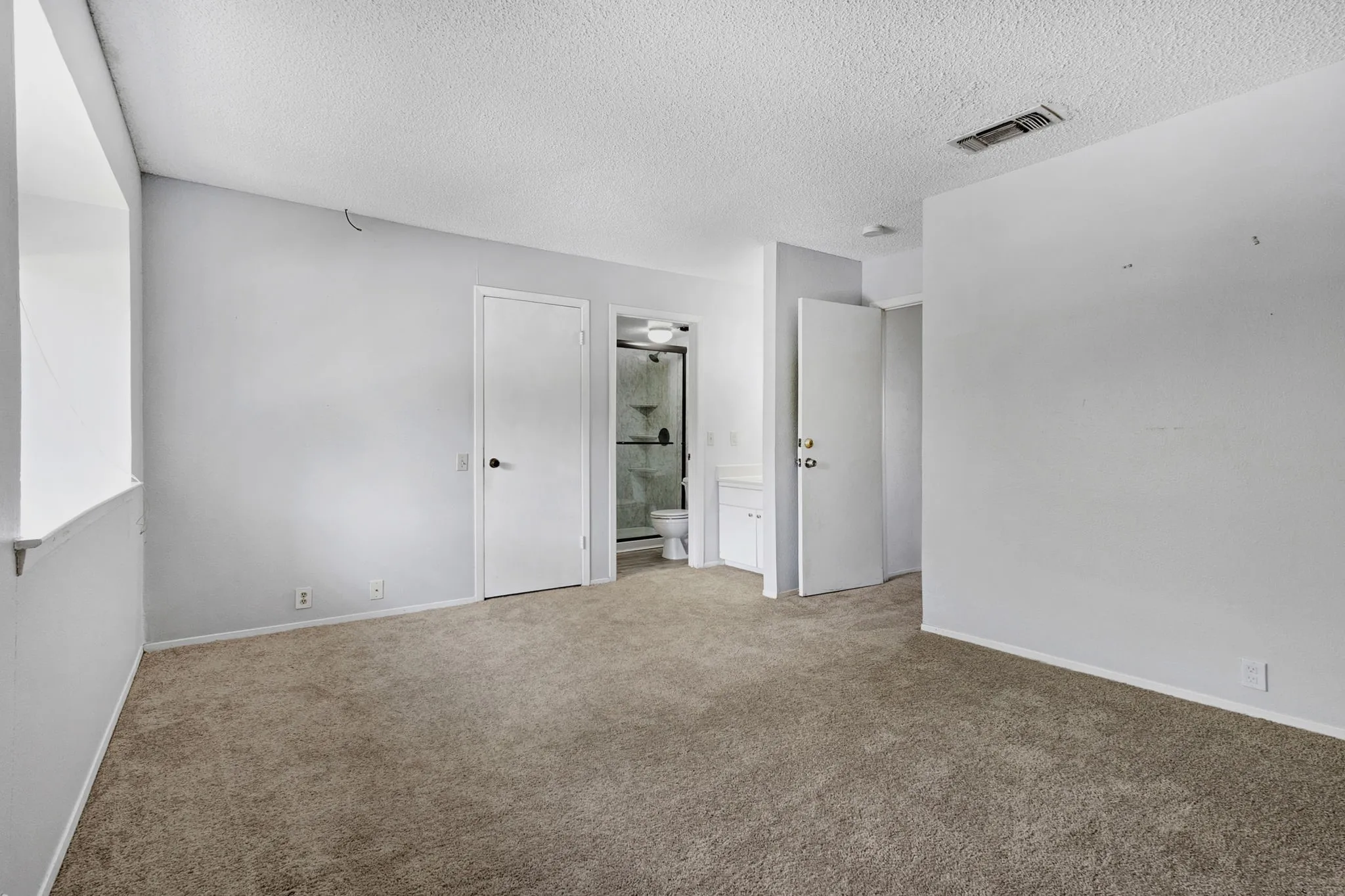 Carpeted room featuring light gray walls and a textured ceiling
