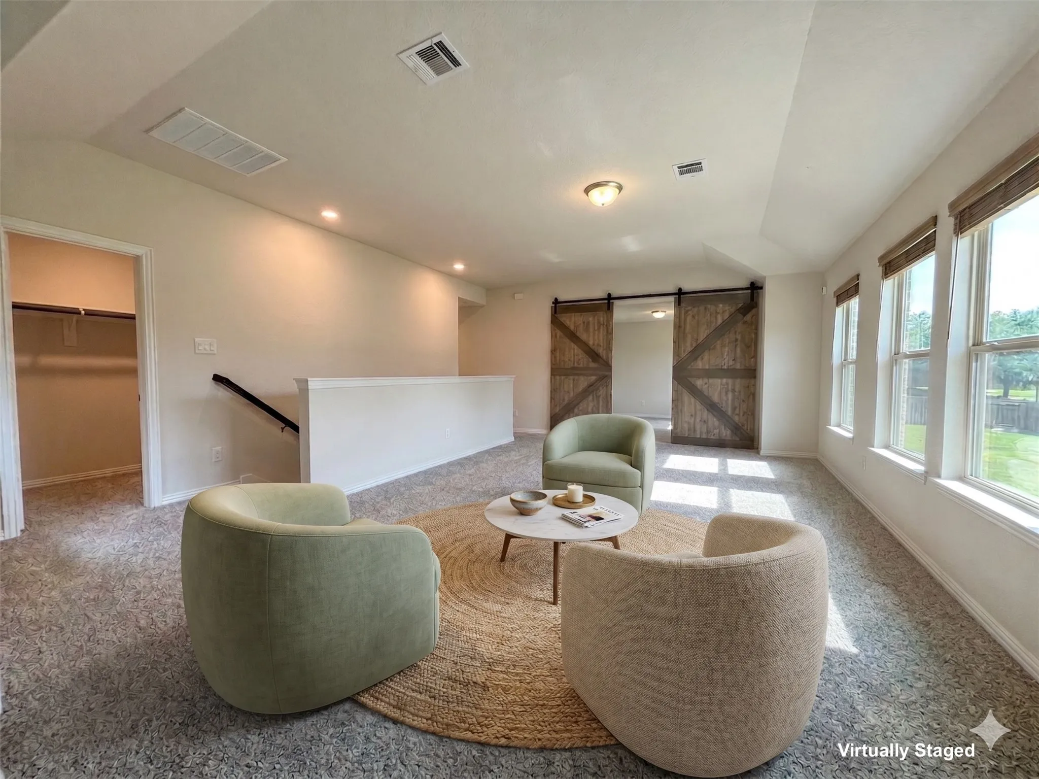 Spacious upper-level room featuring multiple windows with natural light, textured carpeting, recessed lighting, and a pair of sliding barn doors