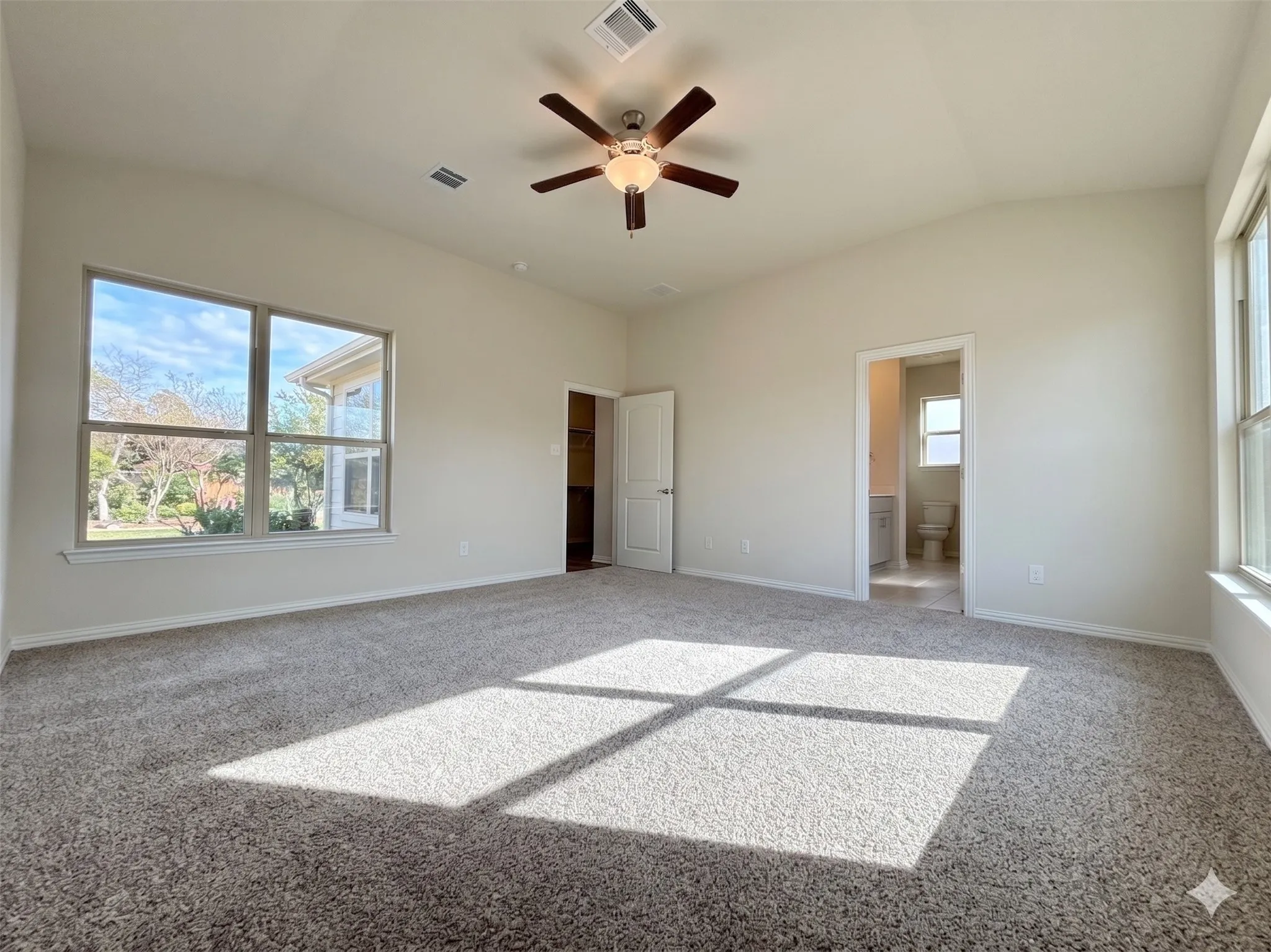 Spacious room featuring vaulted ceilings, a ceiling fan, and plush carpet flooring
