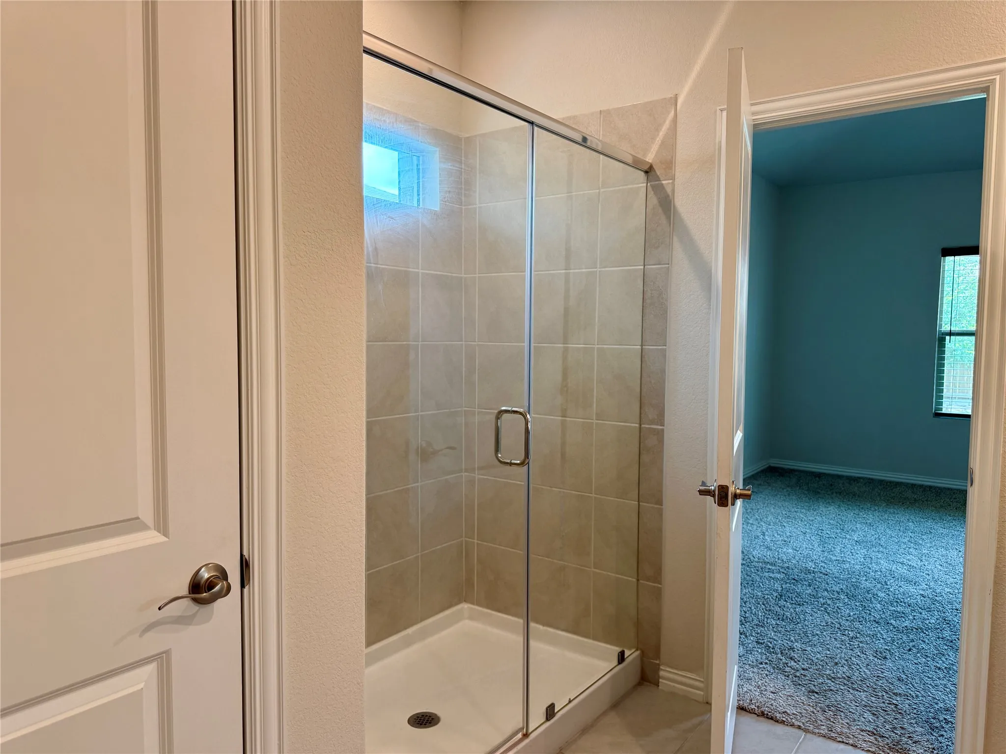 Tiled shower enclosure with a glass sliding door, integrated shower pan, and an upper transom window