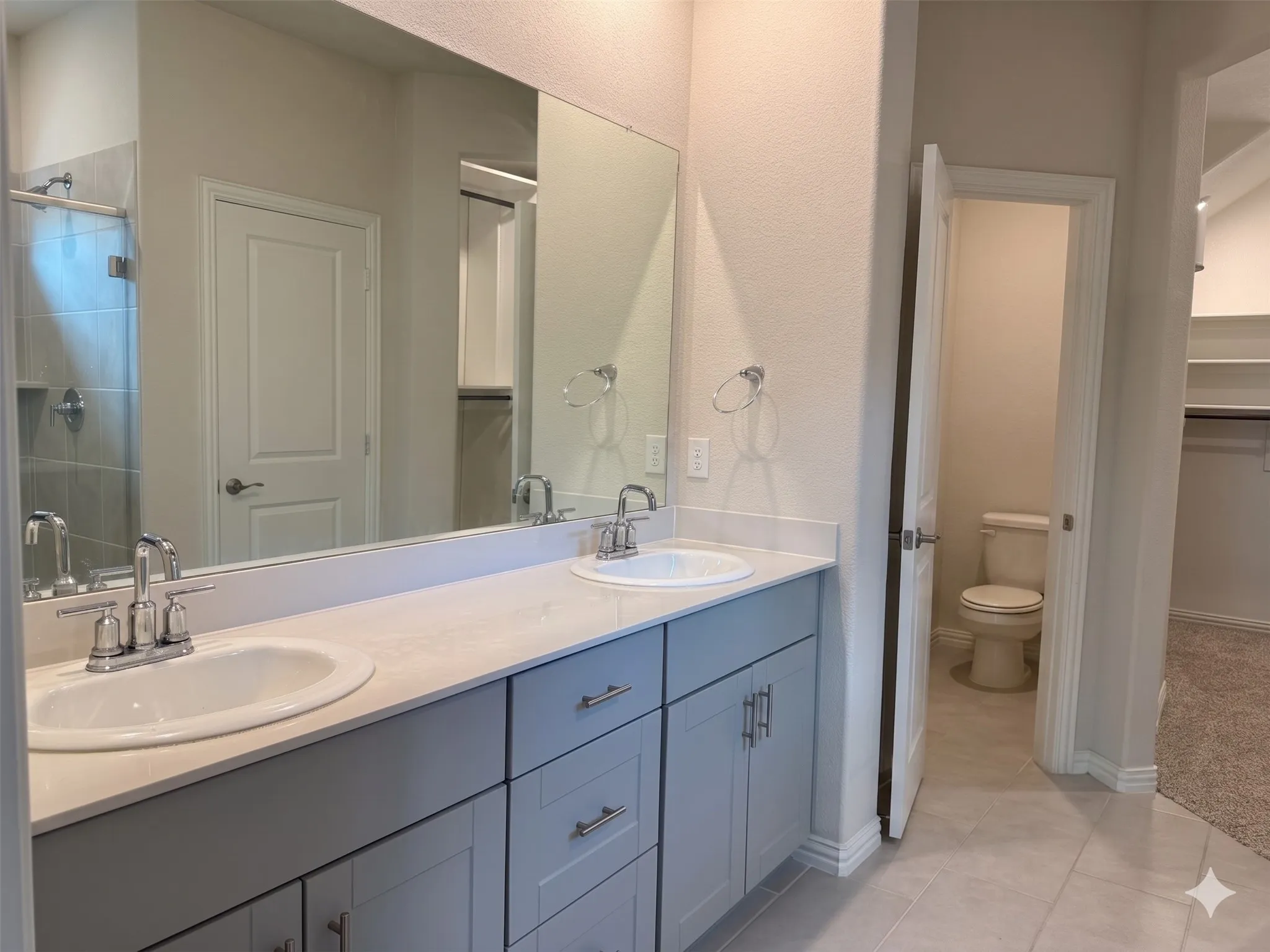 Bathroom vanity featuring dual undermount sinks, chrome fixtures, and a light-colored countertop