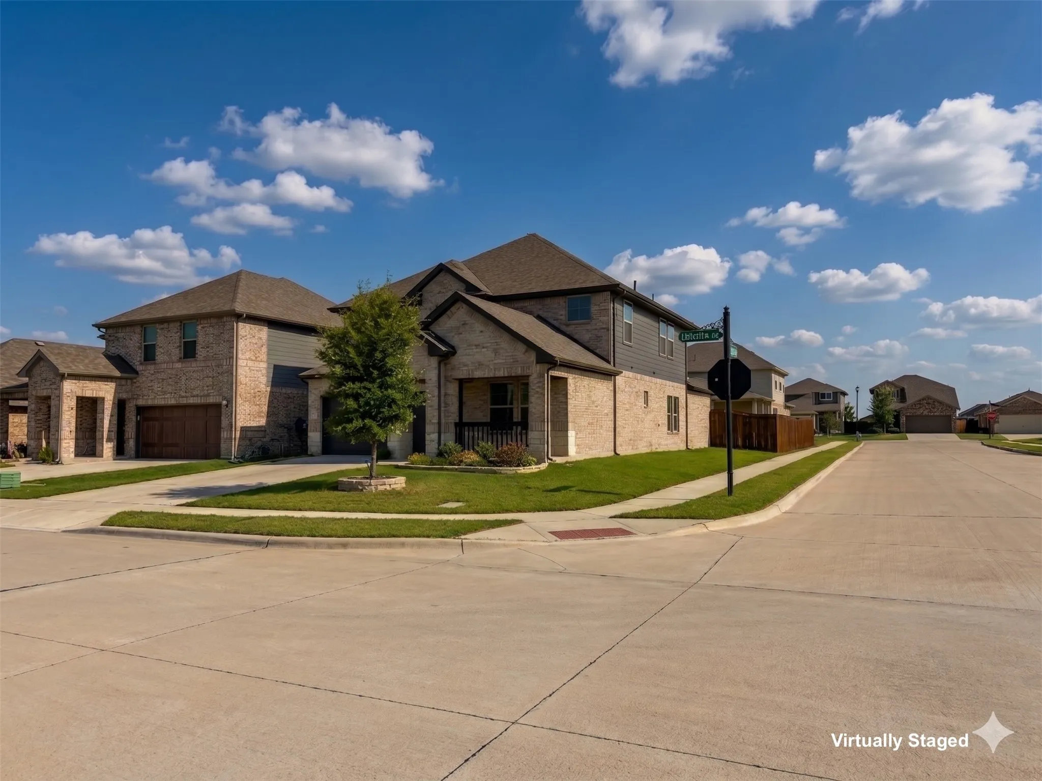 Corner lot residence featuring a brick and siding exterior, an attached two-car garage with a wood-look door, a covered porch, and mature landscaping