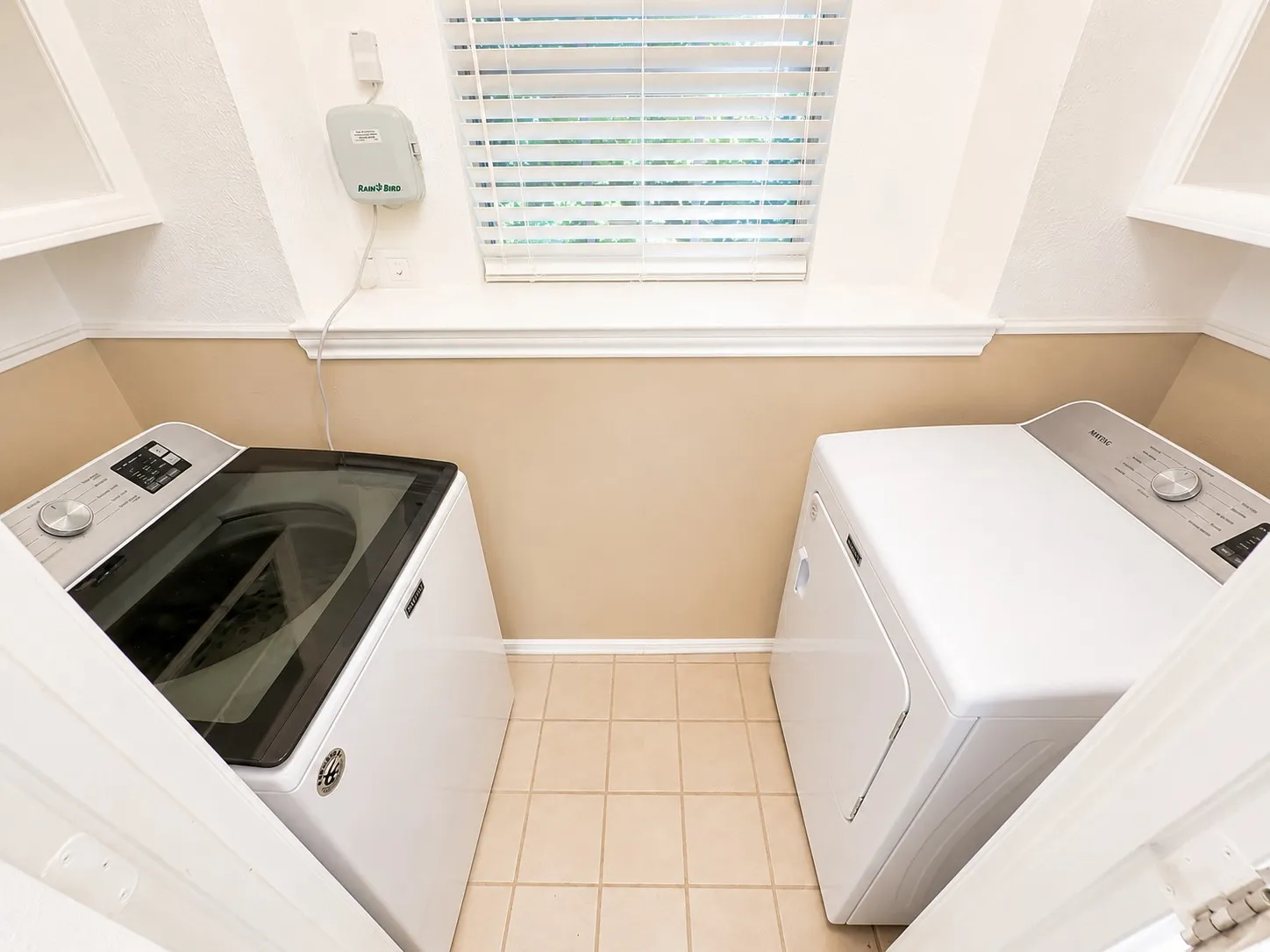Dedicated laundry area featuring tile flooring, white baseboards, and a window with blinds
