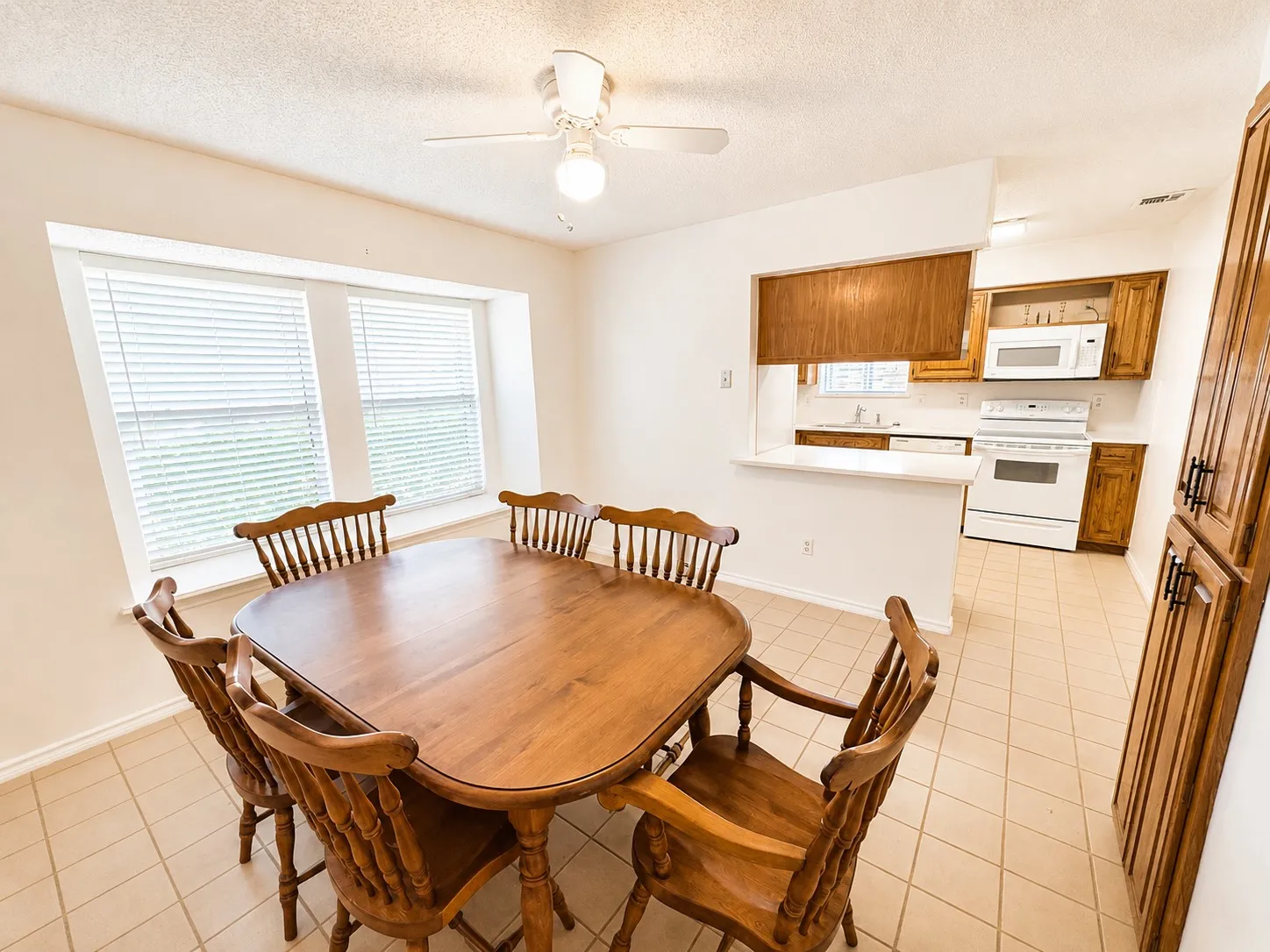 Bright dining area featuring a bay window, ceiling fan, and ceramic tile flooring