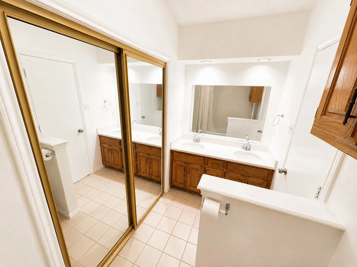 Spacious bathroom featuring a dual vanity with wood cabinetry, integrated sinks, and polished chrome fixtures