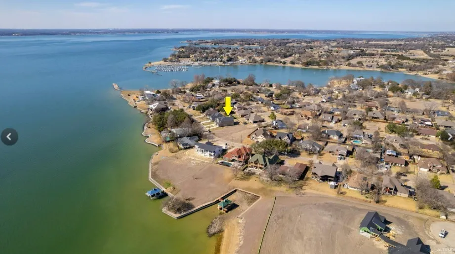Expansive waterfront property featuring a substantial body of water, established residential properties, and clear skies
