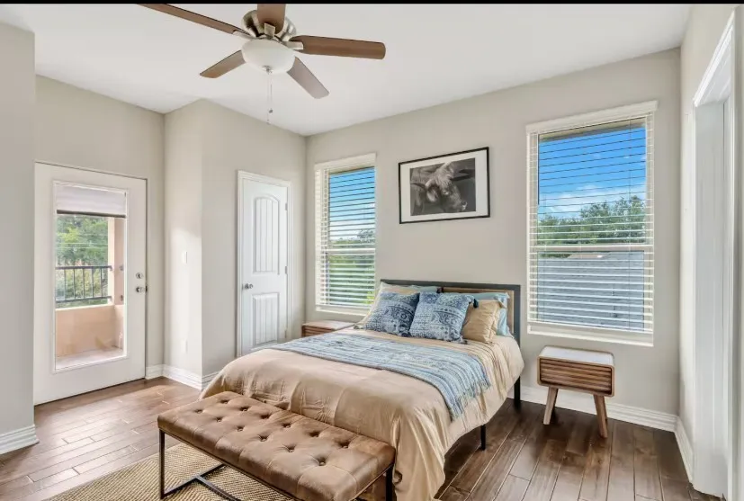 Bedroom with wood-finish flooring, a ceiling fan, and multiple windows