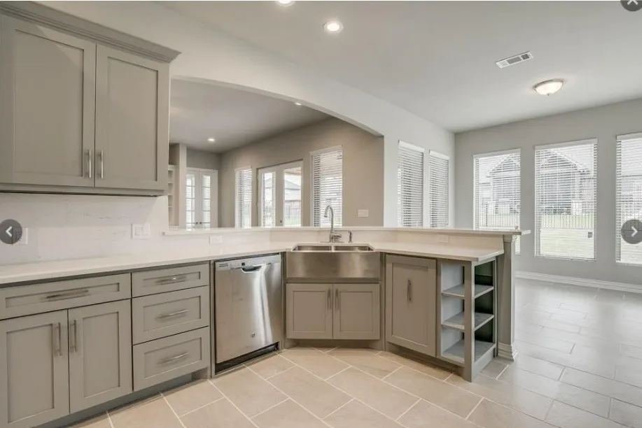 Kitchen featuring gray shaker-style cabinetry, stainless steel appliances, a farmhouse sink, and light-toned countertops