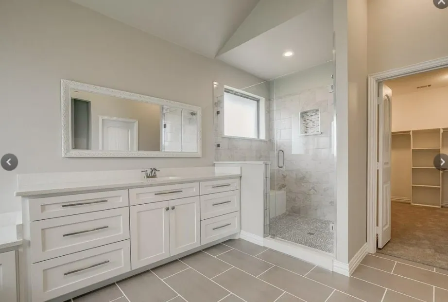 Bathroom featuring a spacious walk-in shower with a built-in bench, glass enclosure, and stone tile surround