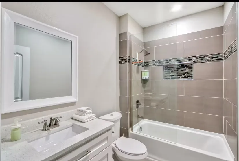 Bathroom featuring a shower-tub combination, a built-in shower niche, and a vanity with an integrated sink and brushed nickel faucet