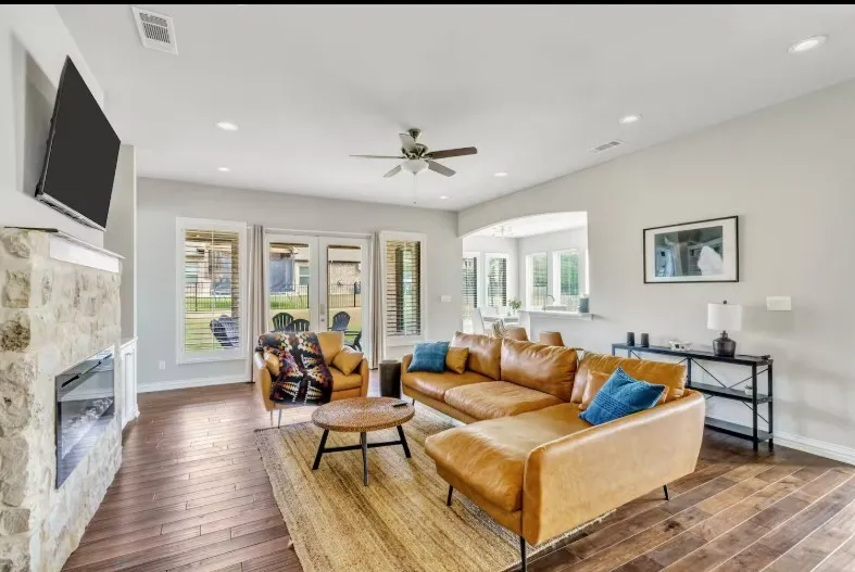 Spacious living area featuring wood-finish flooring and a stone-clad fireplace