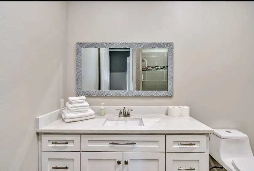 Bathroom vanity featuring a quartz countertop with an undermount sink, brushed nickel faucet, and white shaker-style cabinetry with dark pulls