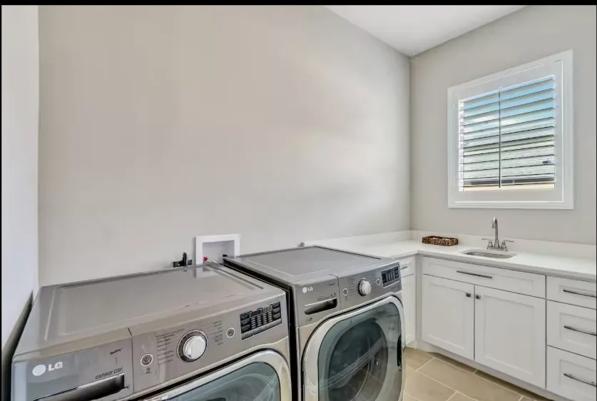 Laundry room featuring a corner sink, white cabinetry, a white countertop, and tiled flooring