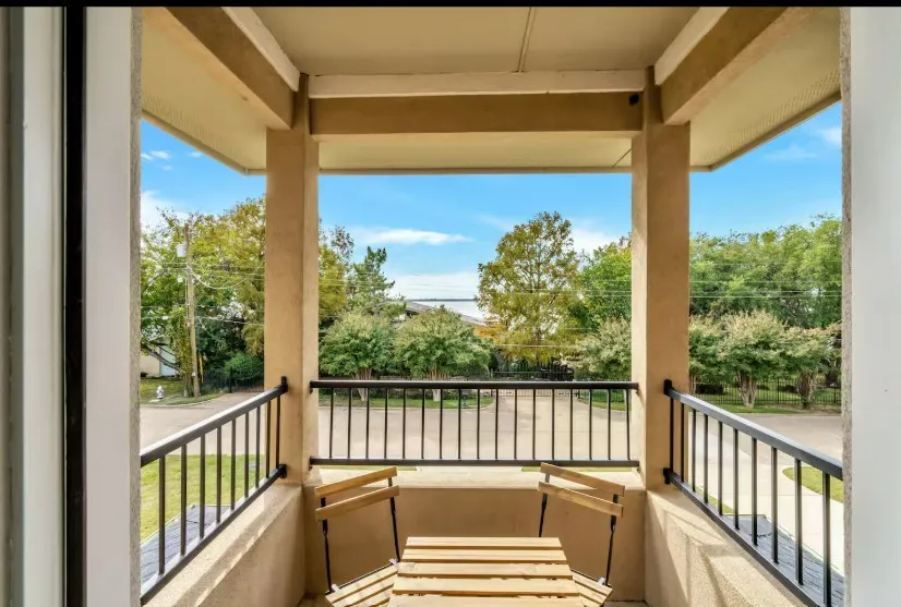Covered private balcony with textured stucco walls, black metal railings, and concrete flooring