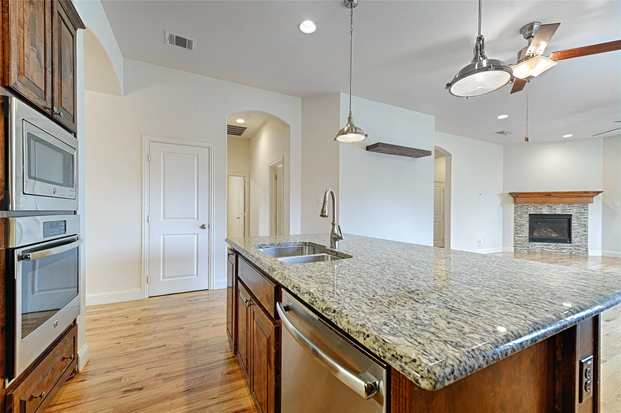 Spacious kitchen island featuring a granite countertop, undermount sink, and stainless steel dishwasher