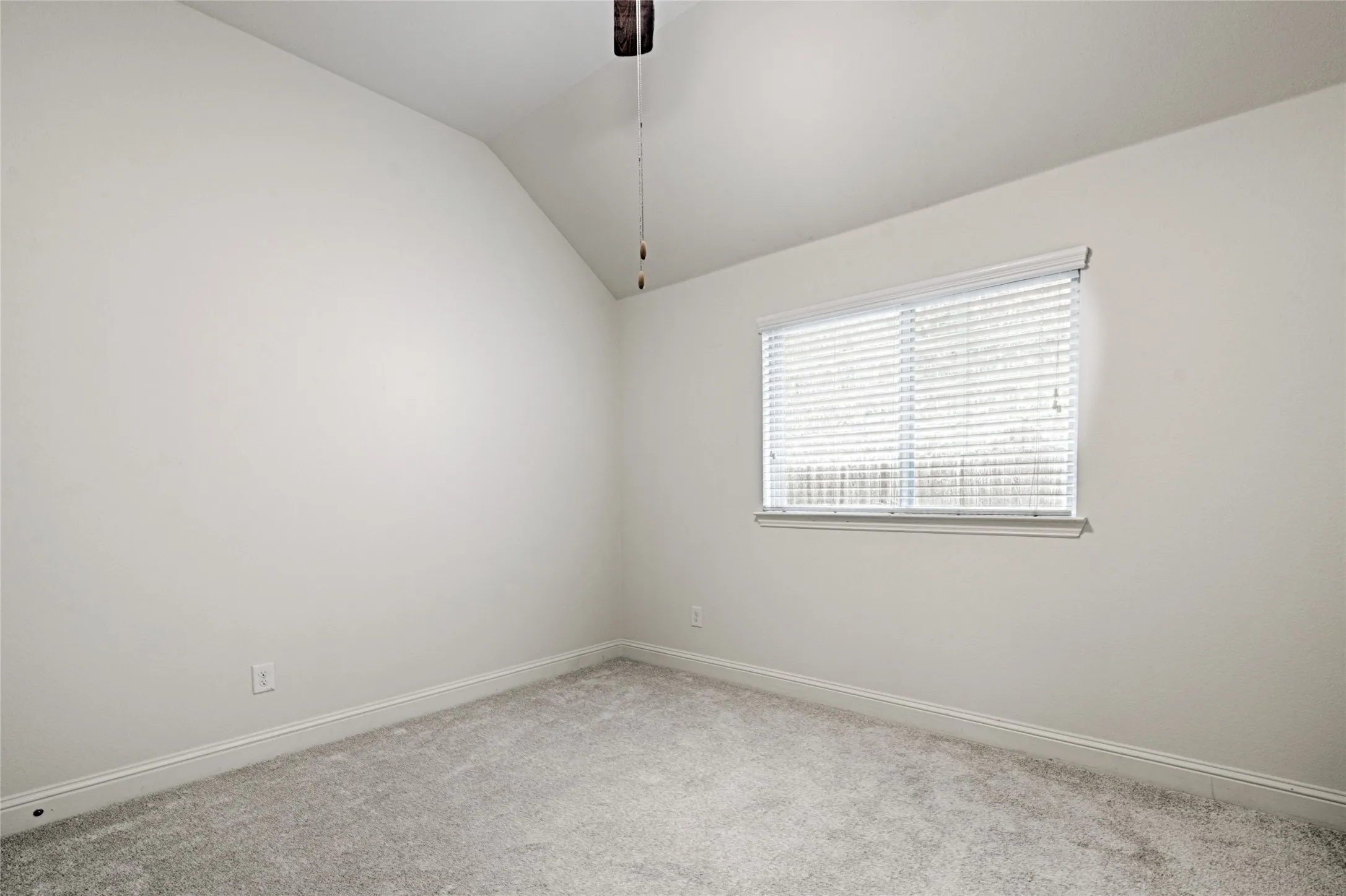 Carpeted room featuring a single window with blinds, a ceiling fan, and sloped ceiling