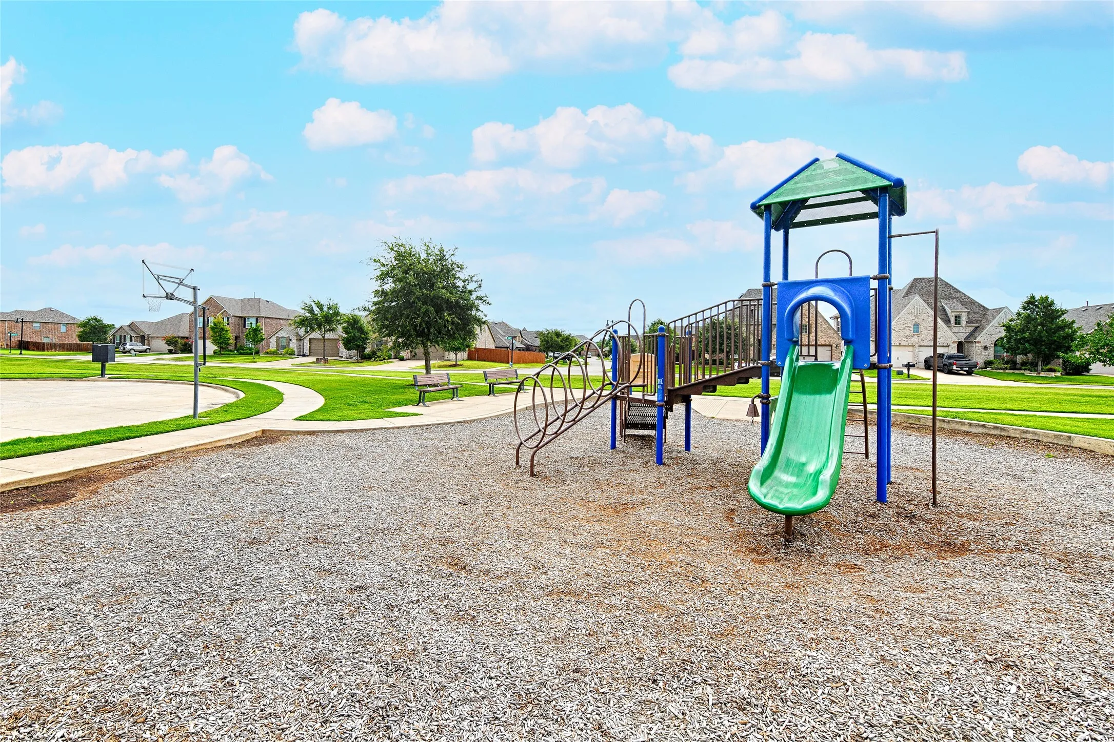 Community playground featuring a multi-level play structure with a slide, swings, and climbing elements