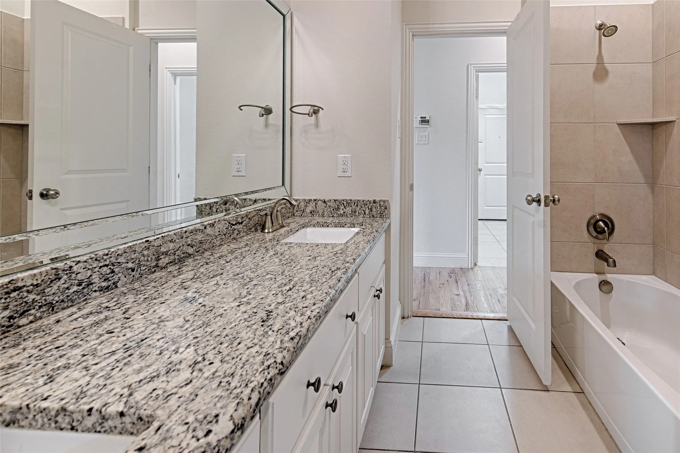Bathroom featuring a white vanity with an undermount sink, a stone countertop, and an expansive wall-mounted mirror