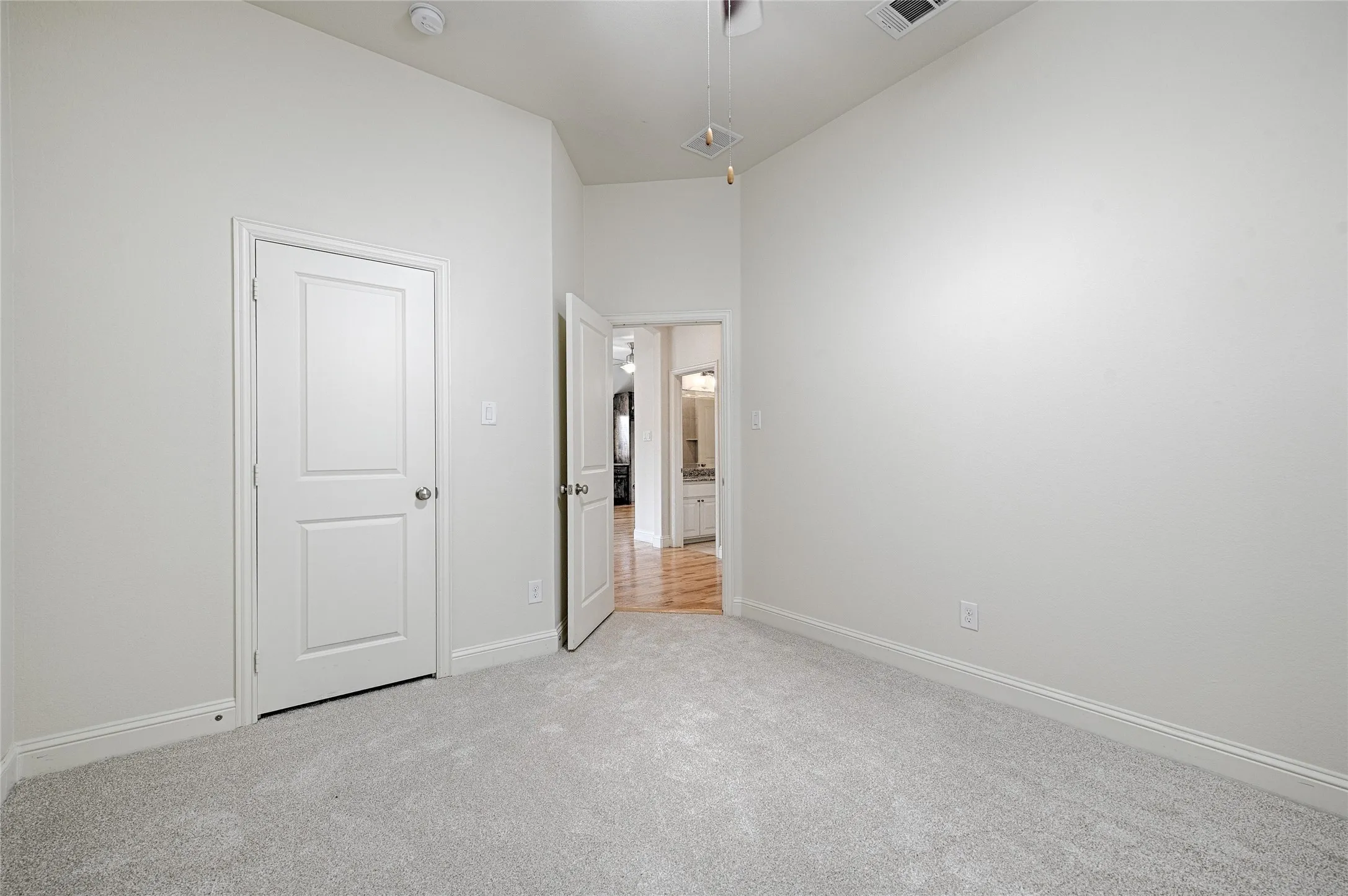 Carpeted room featuring light gray walls, white trim, and a white two-panel door with a brushed nickel knob