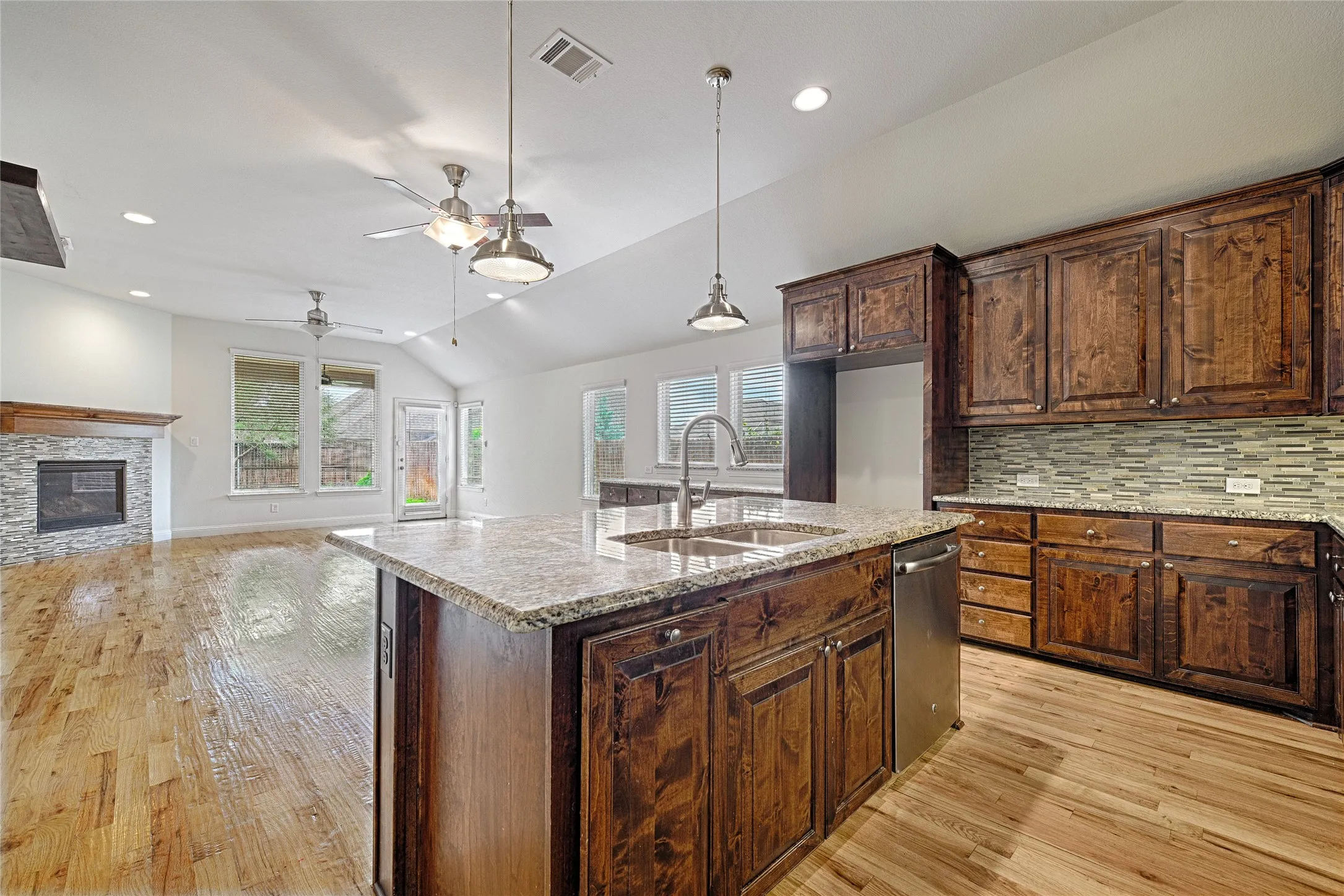 Open-concept living area featuring a kitchen island with granite countertops, stainless steel sink, and pendant lighting