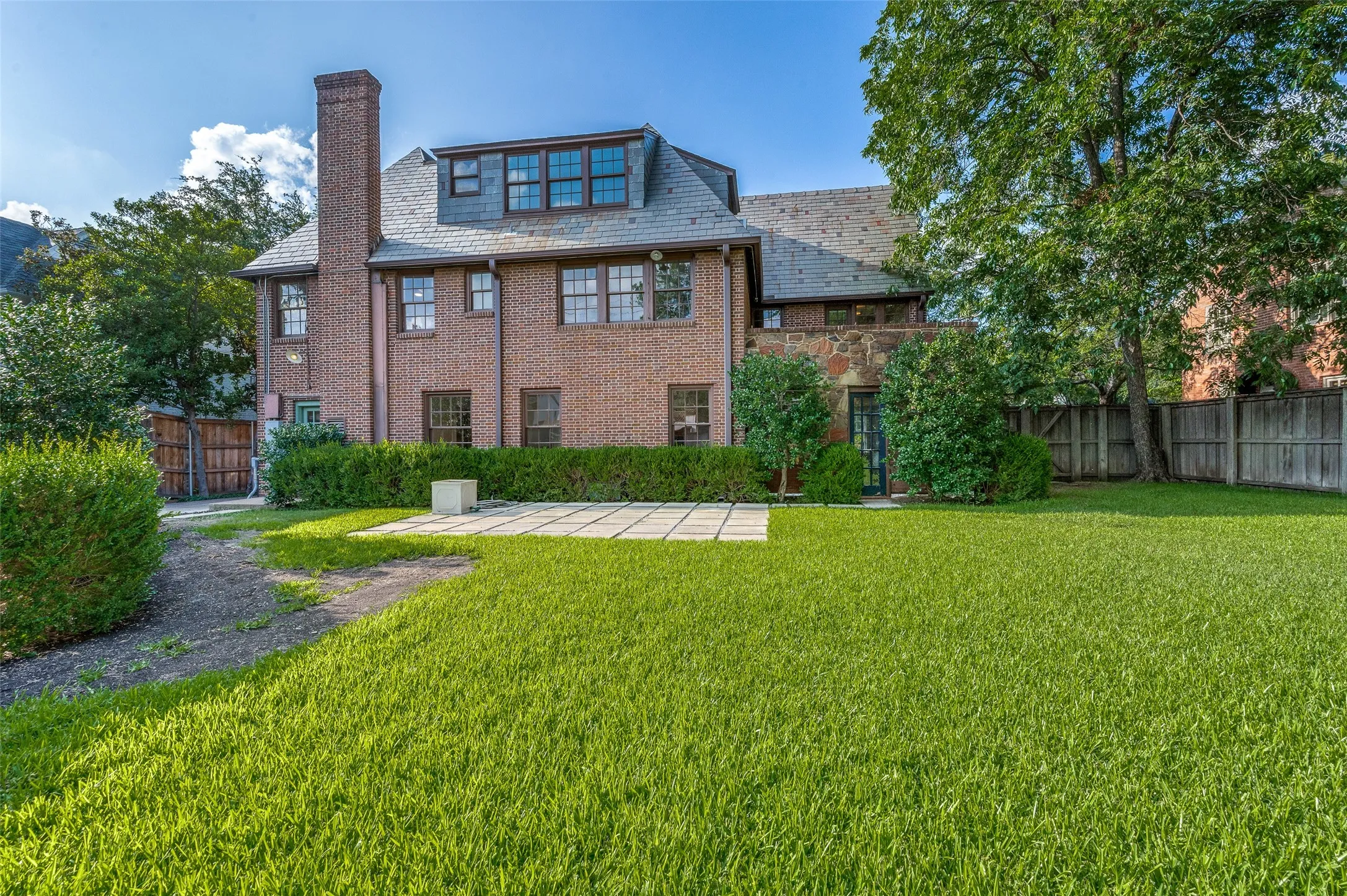 Photo of expansive backyard and back of home with two entrances.