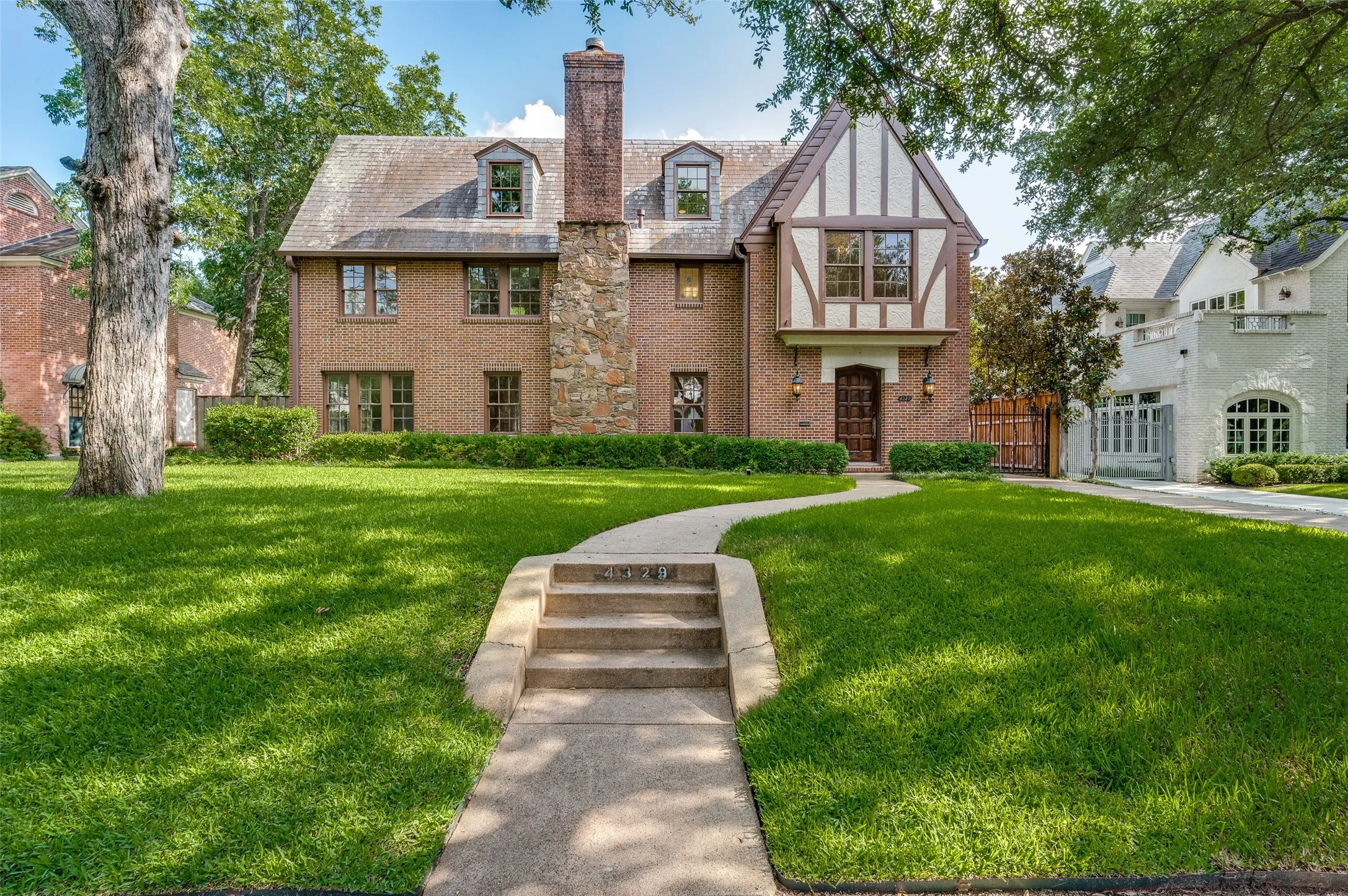 Tudor style home with charming facade and expansive front yard.